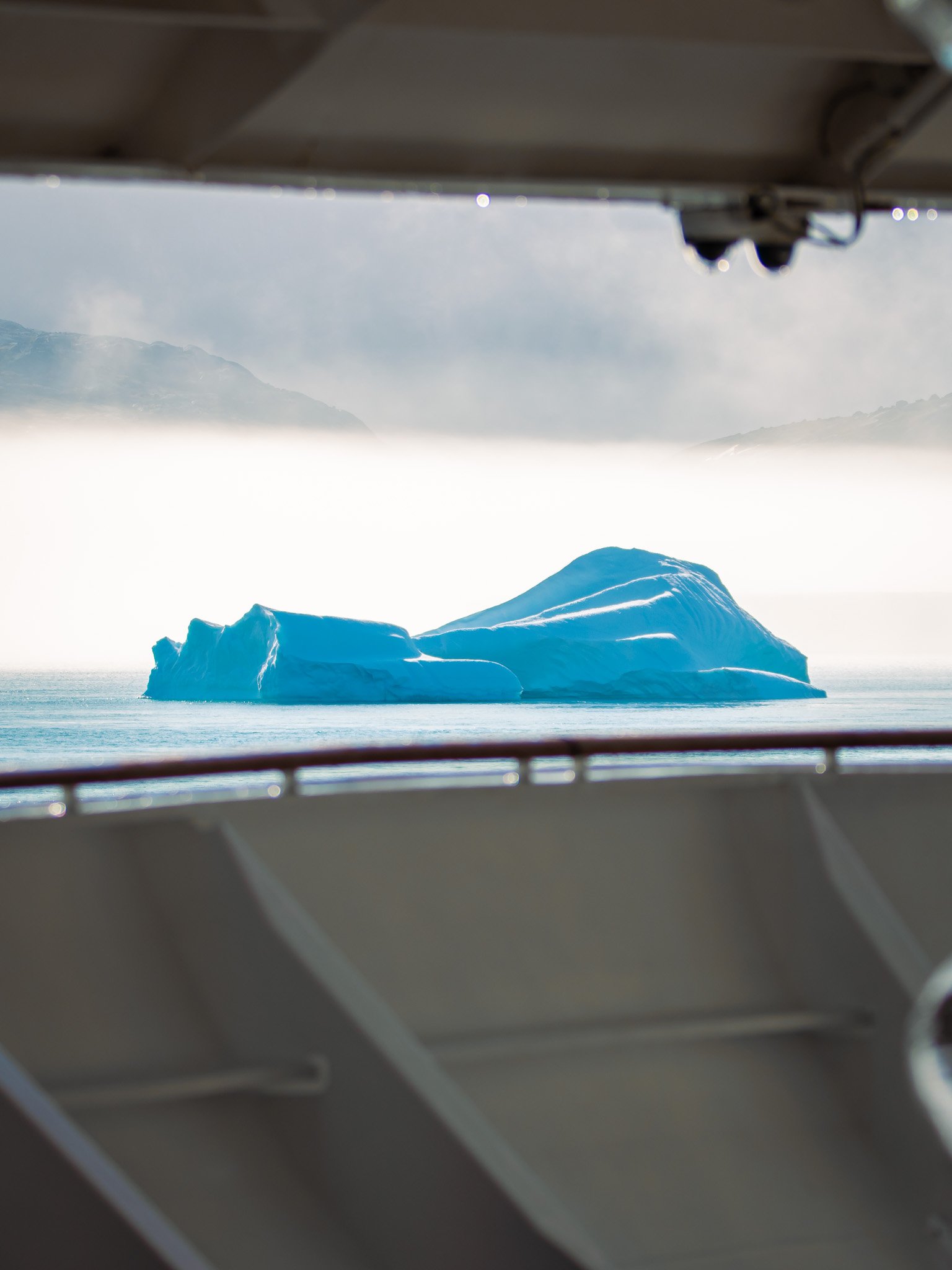 Iceberg floating in the ocean seen through a window.