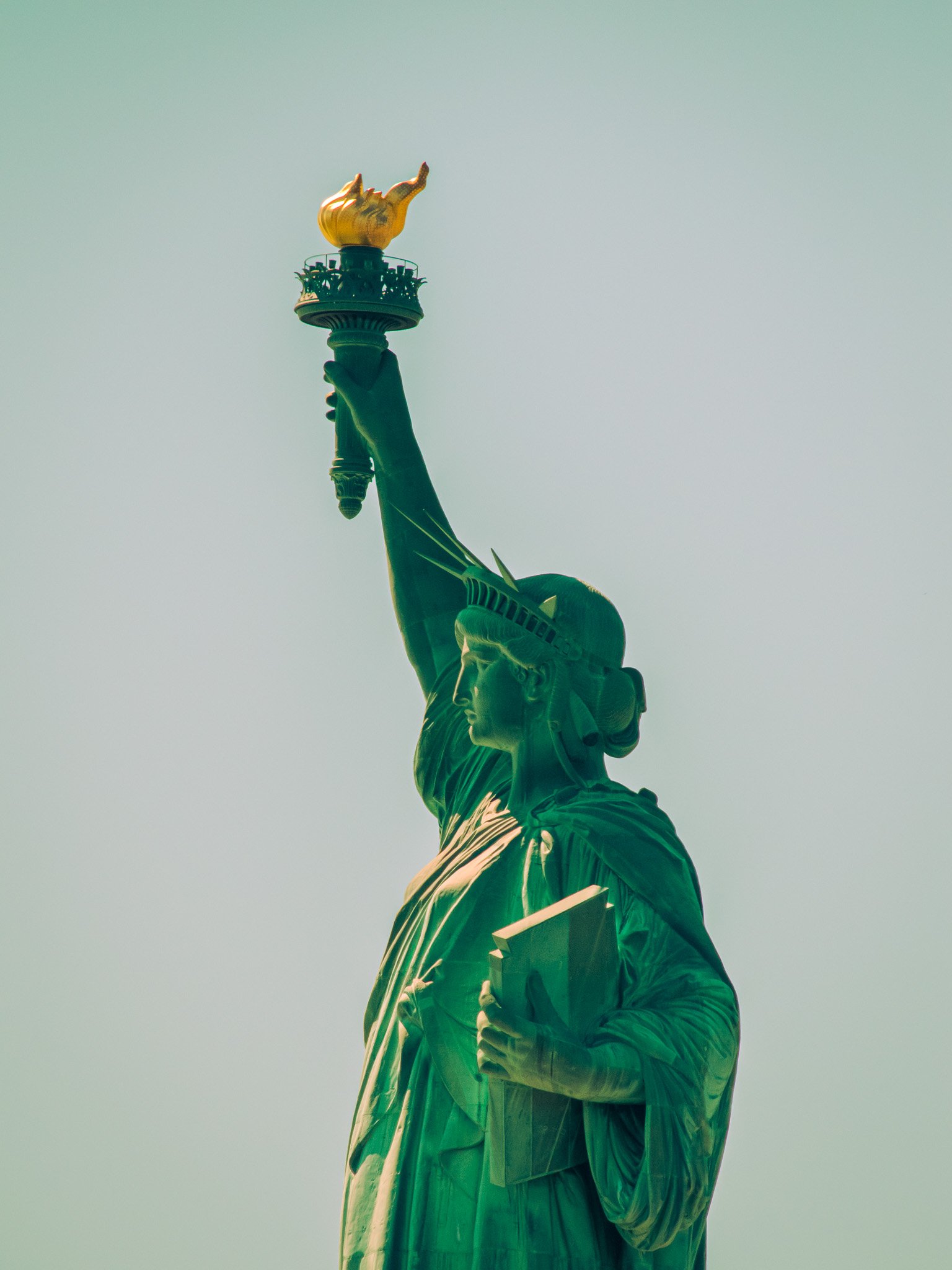Close-up view of the Statue of Liberty holding a torch with a flame at the top.