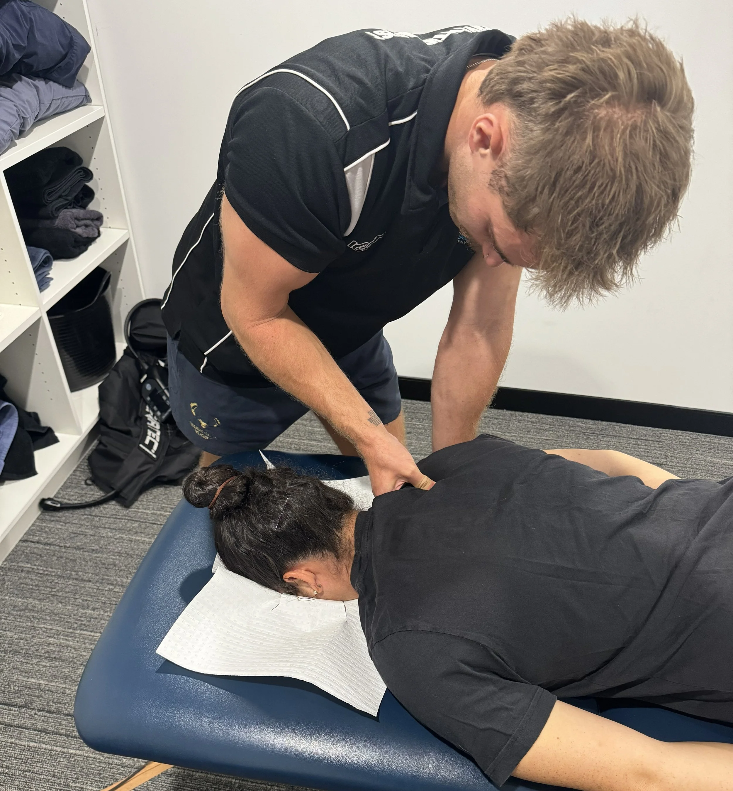 Physical therapist assisting a young woman in arm rehabilitation exercises in a clinical setting.