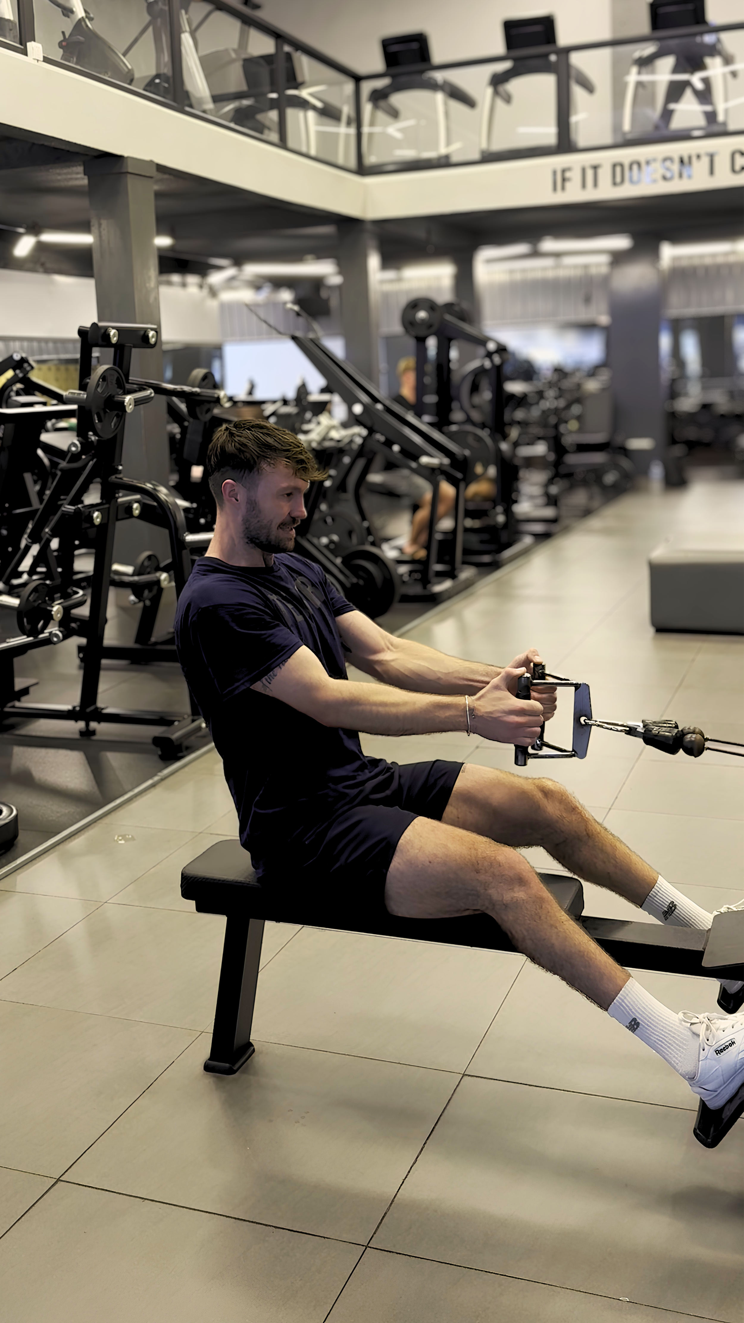 A man in a gym performing seated cable rows for back muscles.