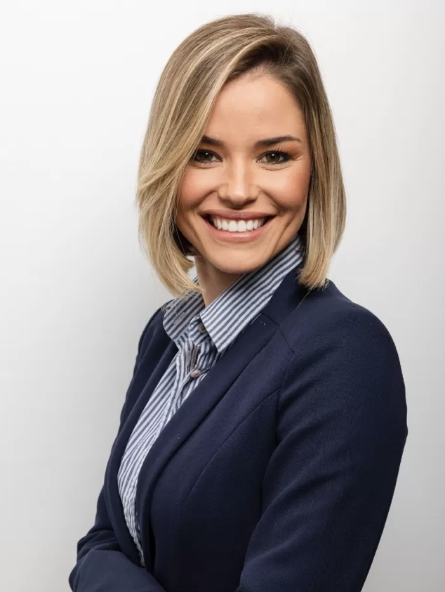 A smiling woman with blonde hair in a professional navy blazer and striped shirt against a plain white background.