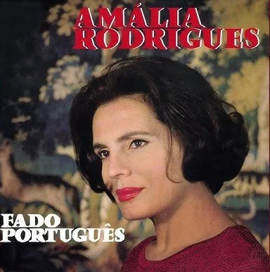 Album cover featuring Amália Rodrigues with dark hair, red lipstick, wearing a red top, against a cloudy sky background, with the text "Amália Rodrigues" and "Fado Portugues"