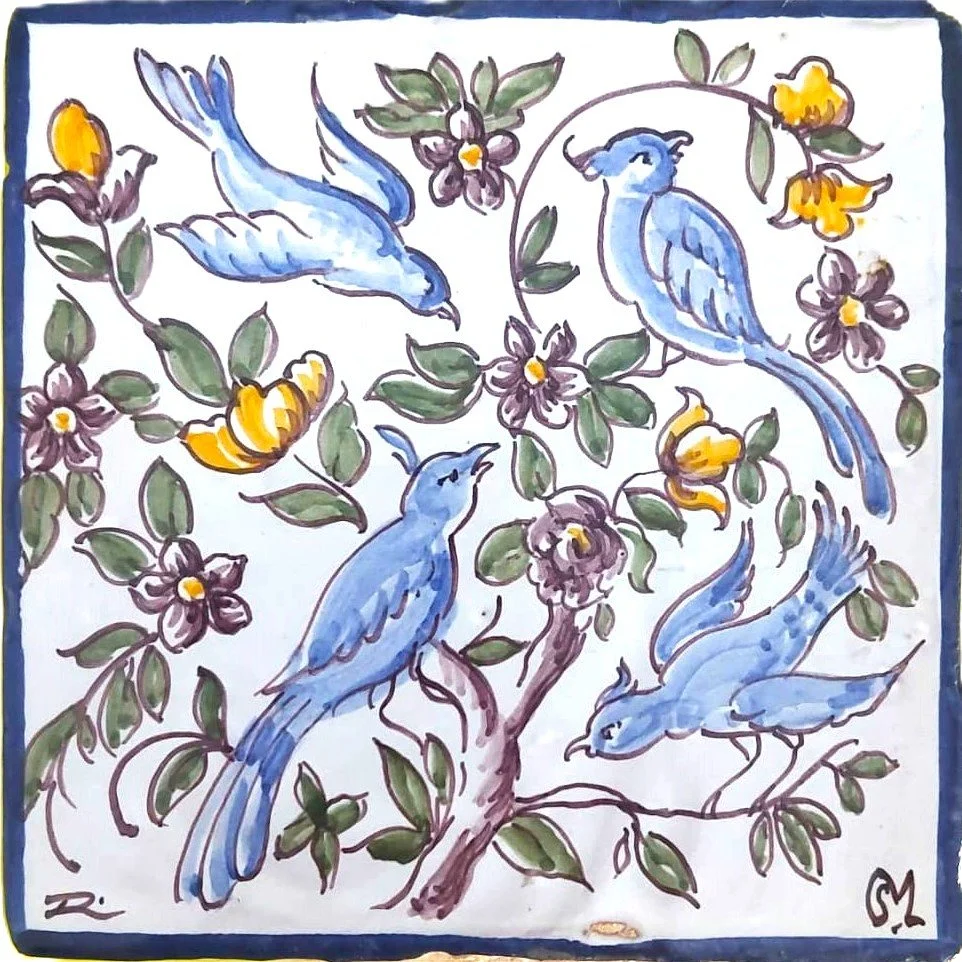 Watercolor painting of five blue birds perched on and flying around a tree with purple and yellow flowers and green leaves.