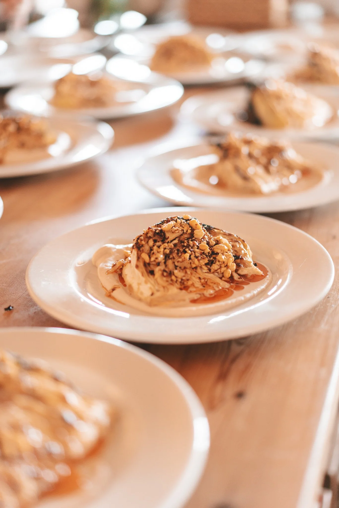 Postre de helado cubierto con nueces picadas y jarabe en un plato blanco.