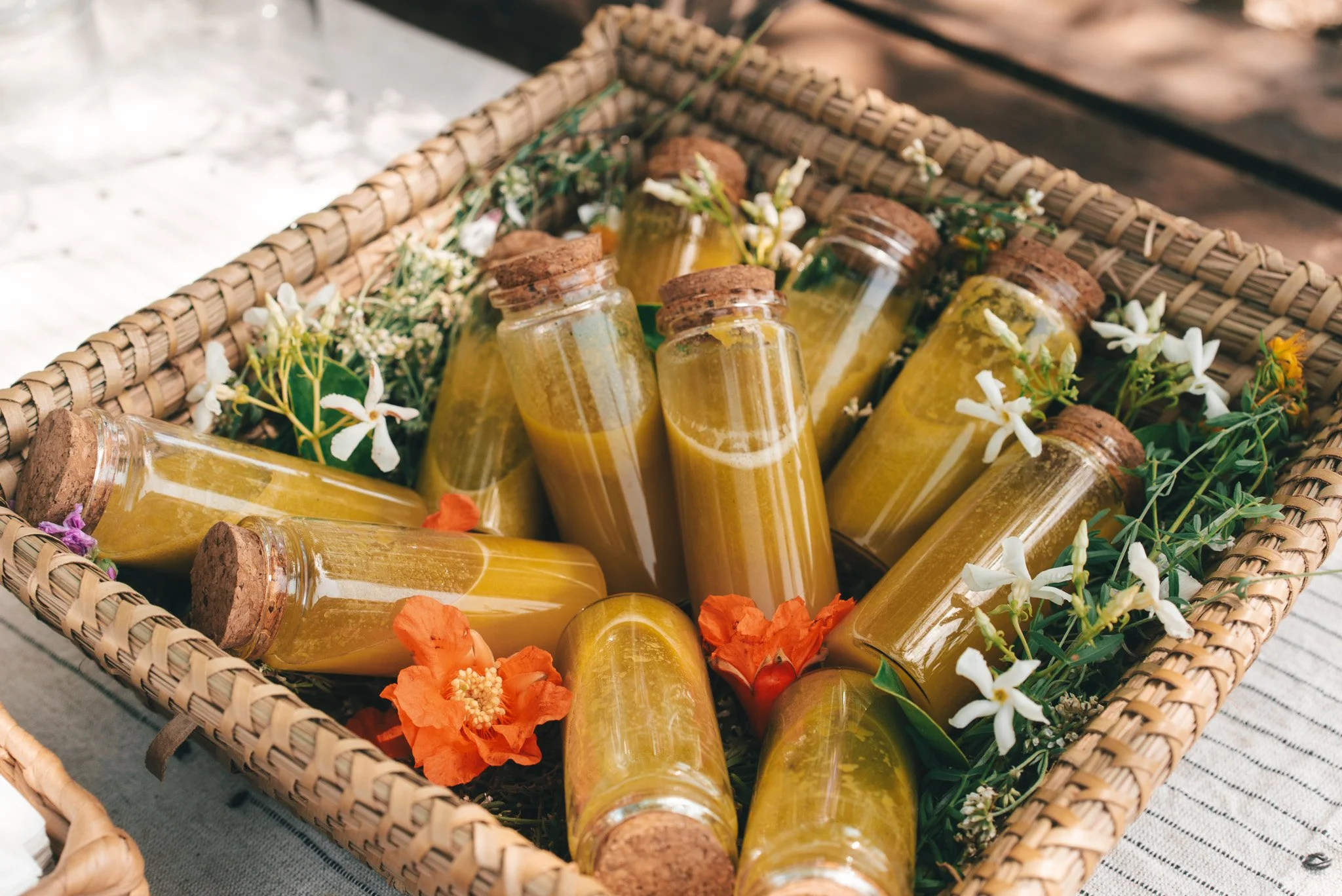 Frascos de miel en una cesta de mimbre decorada con flores blancas y naranjas.
