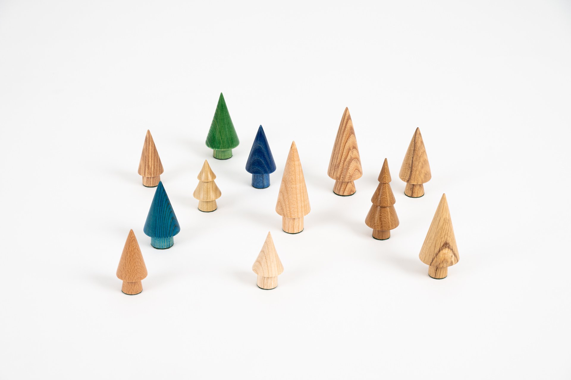 A collection of small wooden and painted toy trees arranged on a white background.