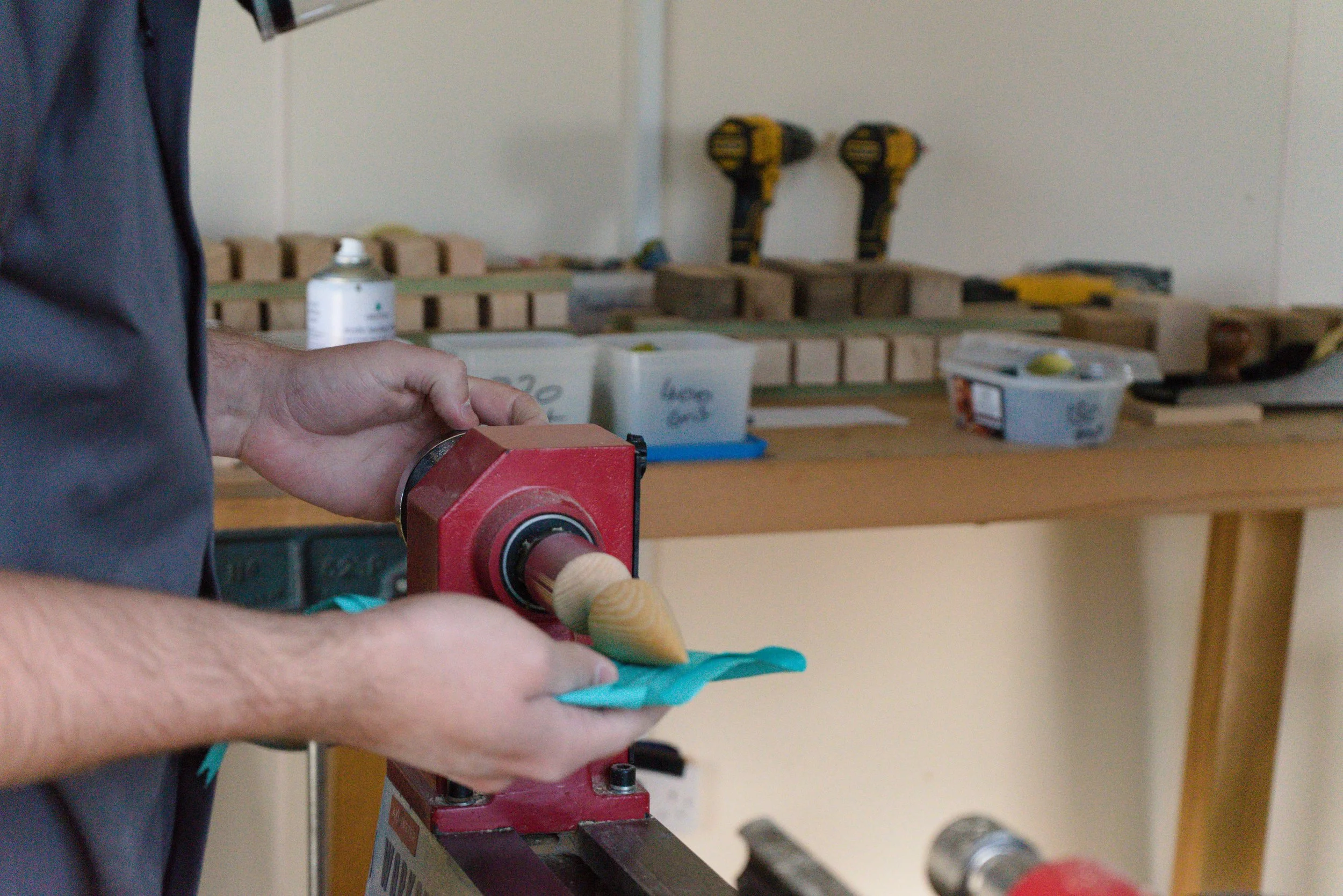 Person working with a lathe machine in a woodworking shop, shaping a wooden piece.