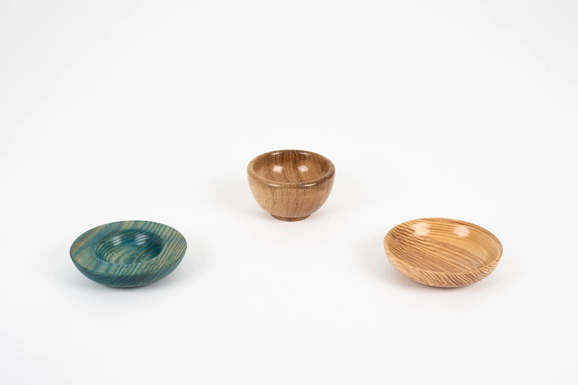 Three small wooden bowls on a white background, one in the center and two on either side.