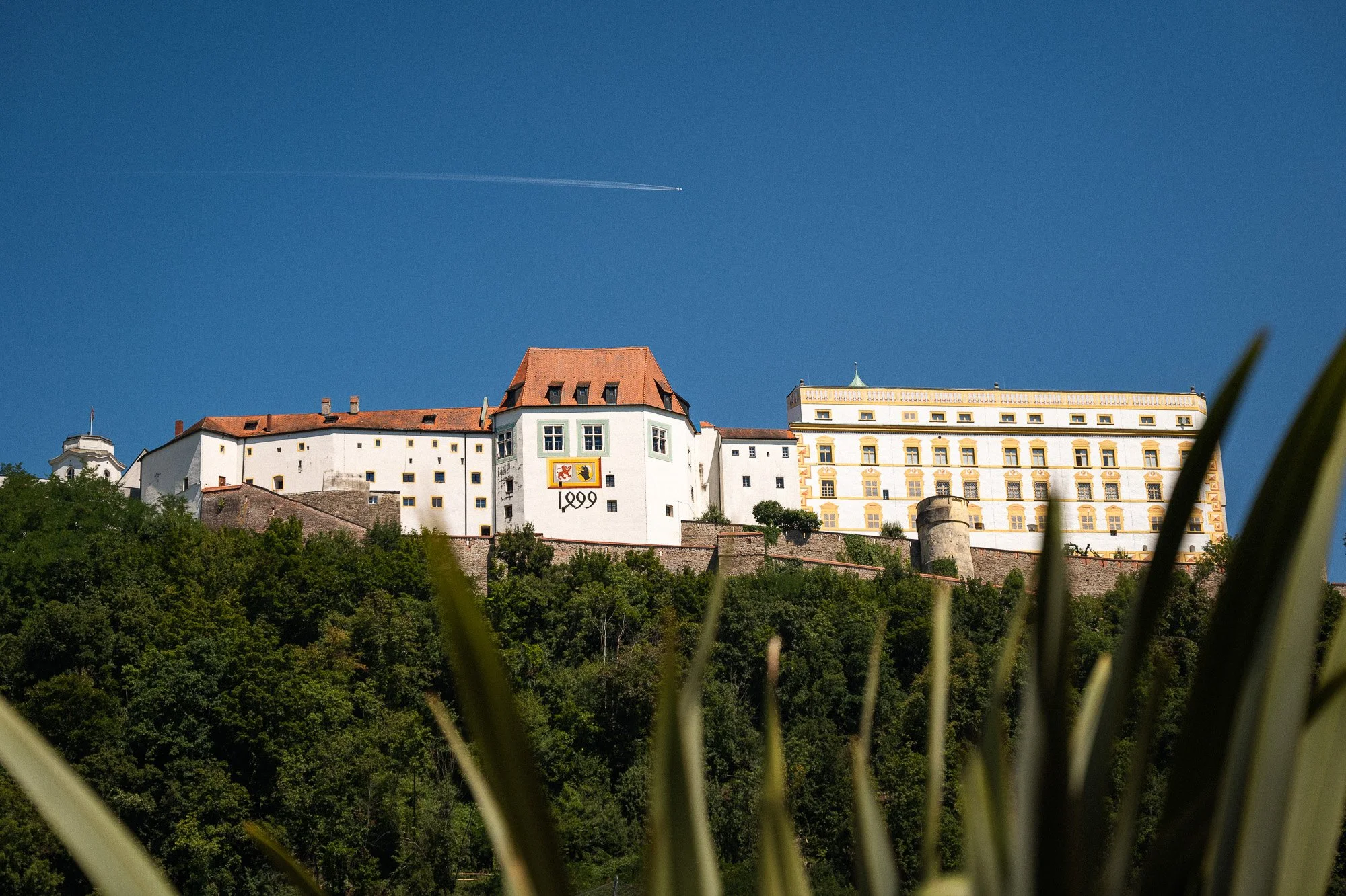 Burg auf einem Hügel mit blauer Himmel und einem Flugzeug am Himmel