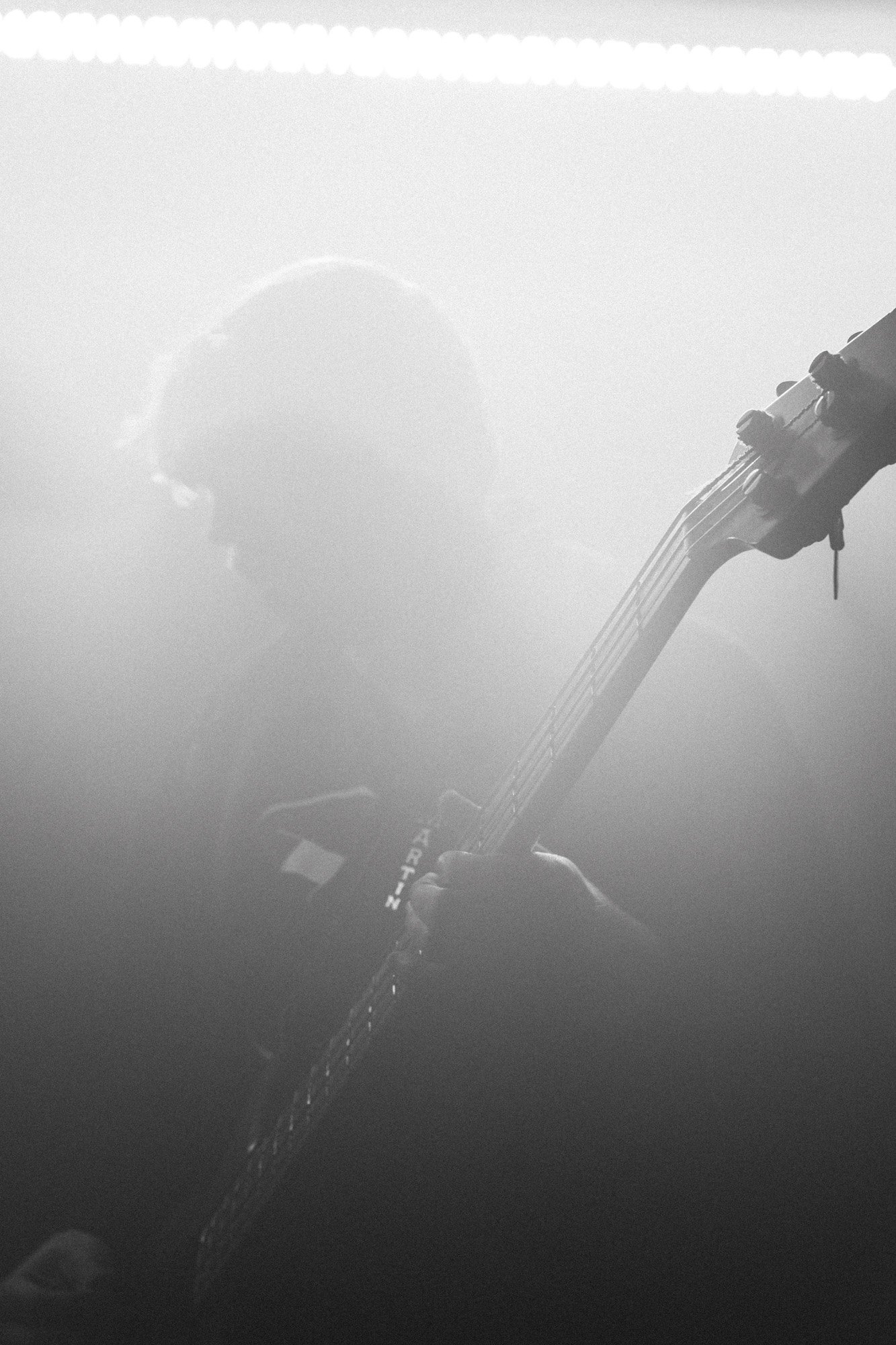 Schwarz-weiß-Foto eines Gitarrenspielers, der im Schatten steht, mit Fokus auf die Gitarre.