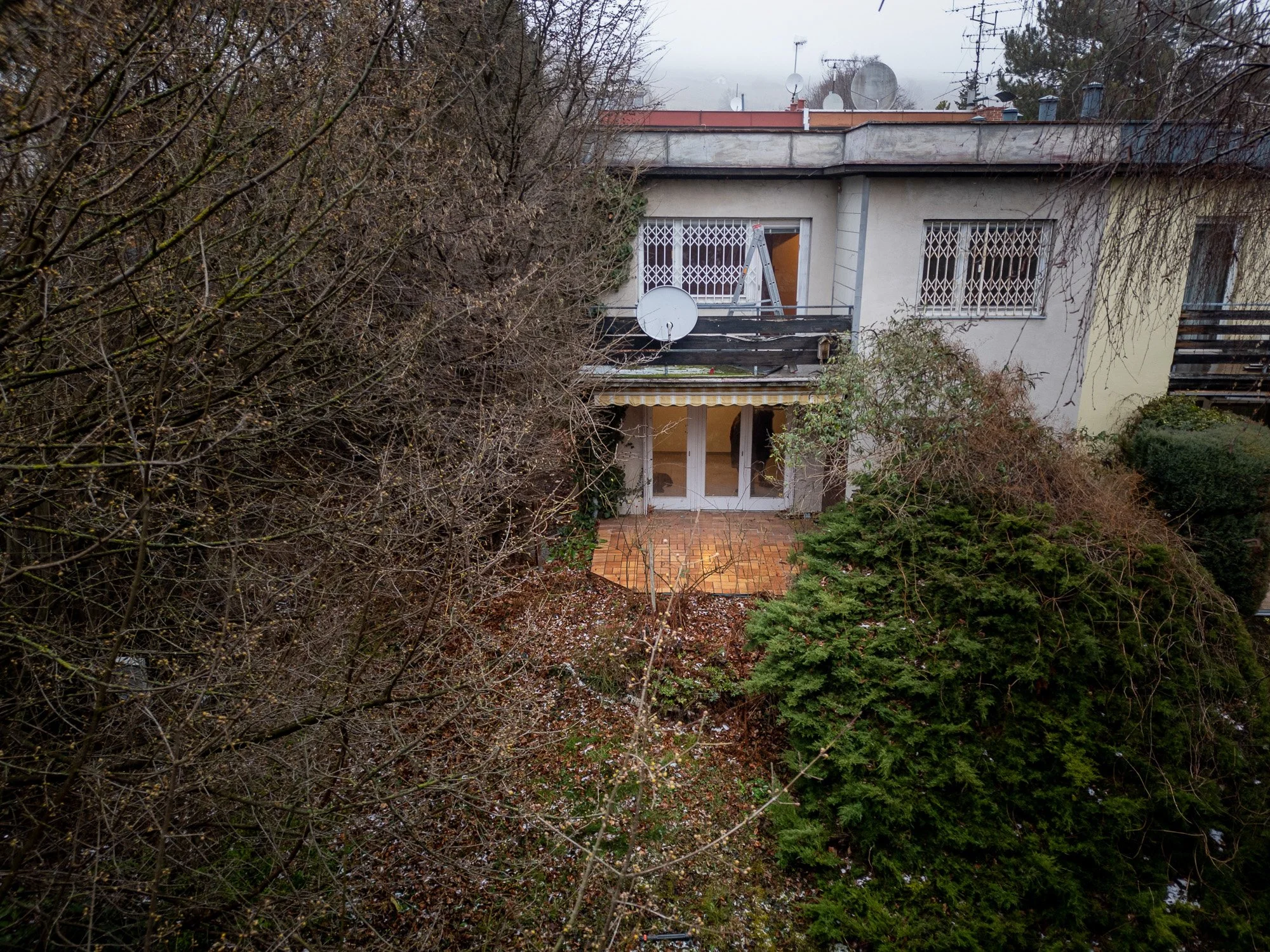 Mehrfamilienhaus mit Terrasse und umliegendem Garten, im Winter mit wenig Laub