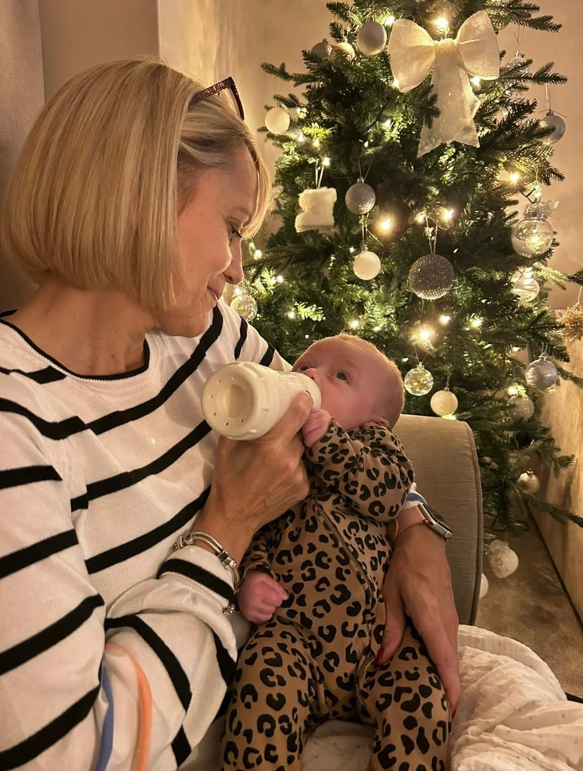 A smiling woman holding a folder in an office setting with plants and modern decor.