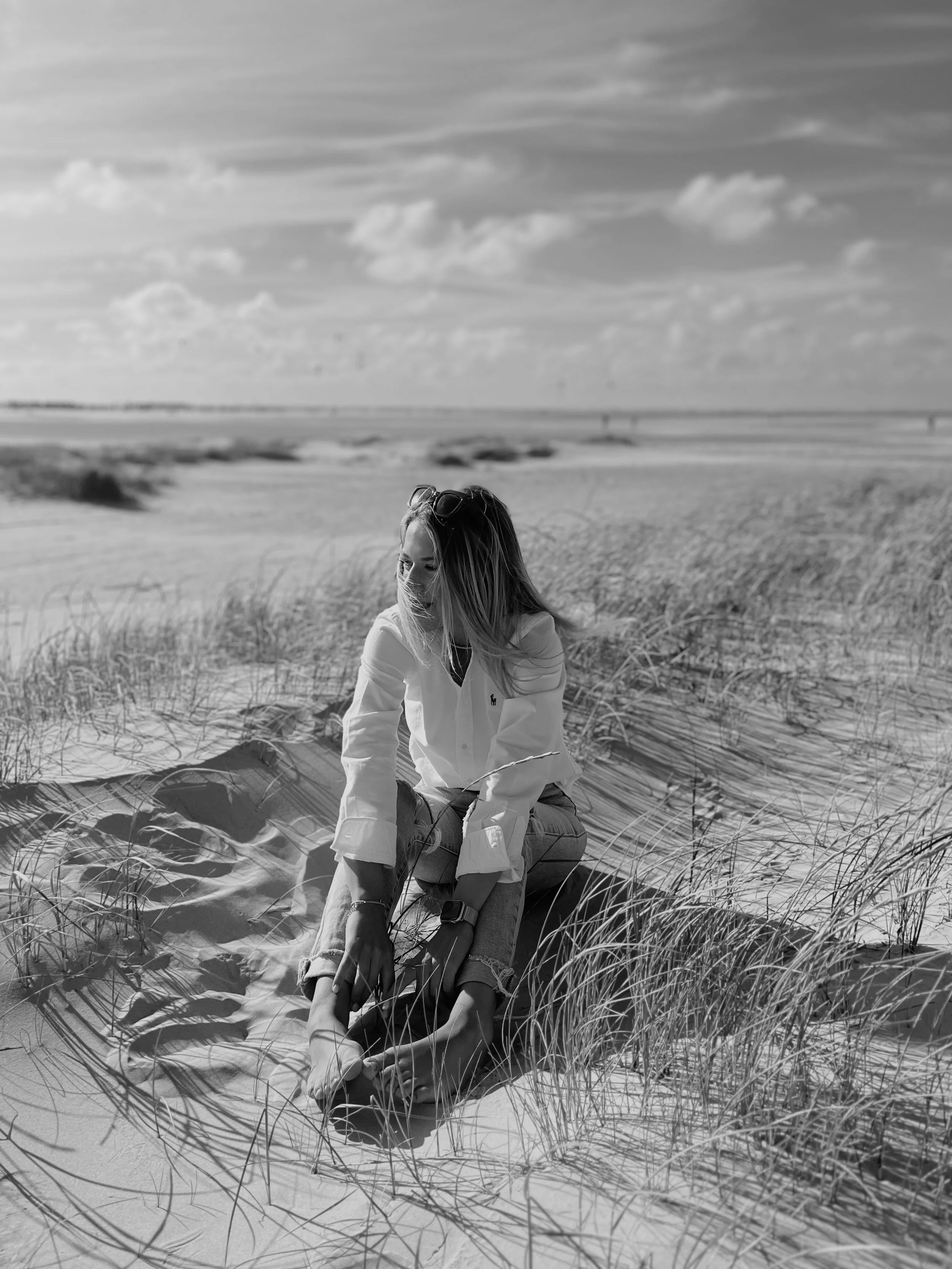 Sanddünen am Strand, umgeben von Gräsern, bei sonnigem Himmel, in Schwarz-Weiß
