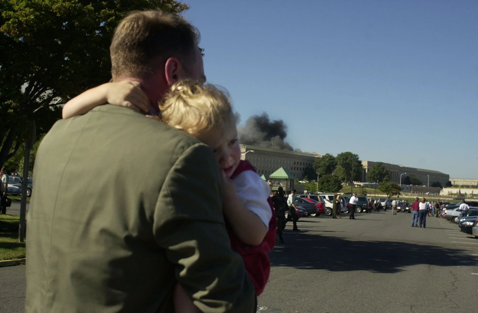A father runs with his two children as smoke rises from the Pentagon on the morning of September 11th, 2001 after American Airlines flight 77 was hijacked and crashed into the building.
