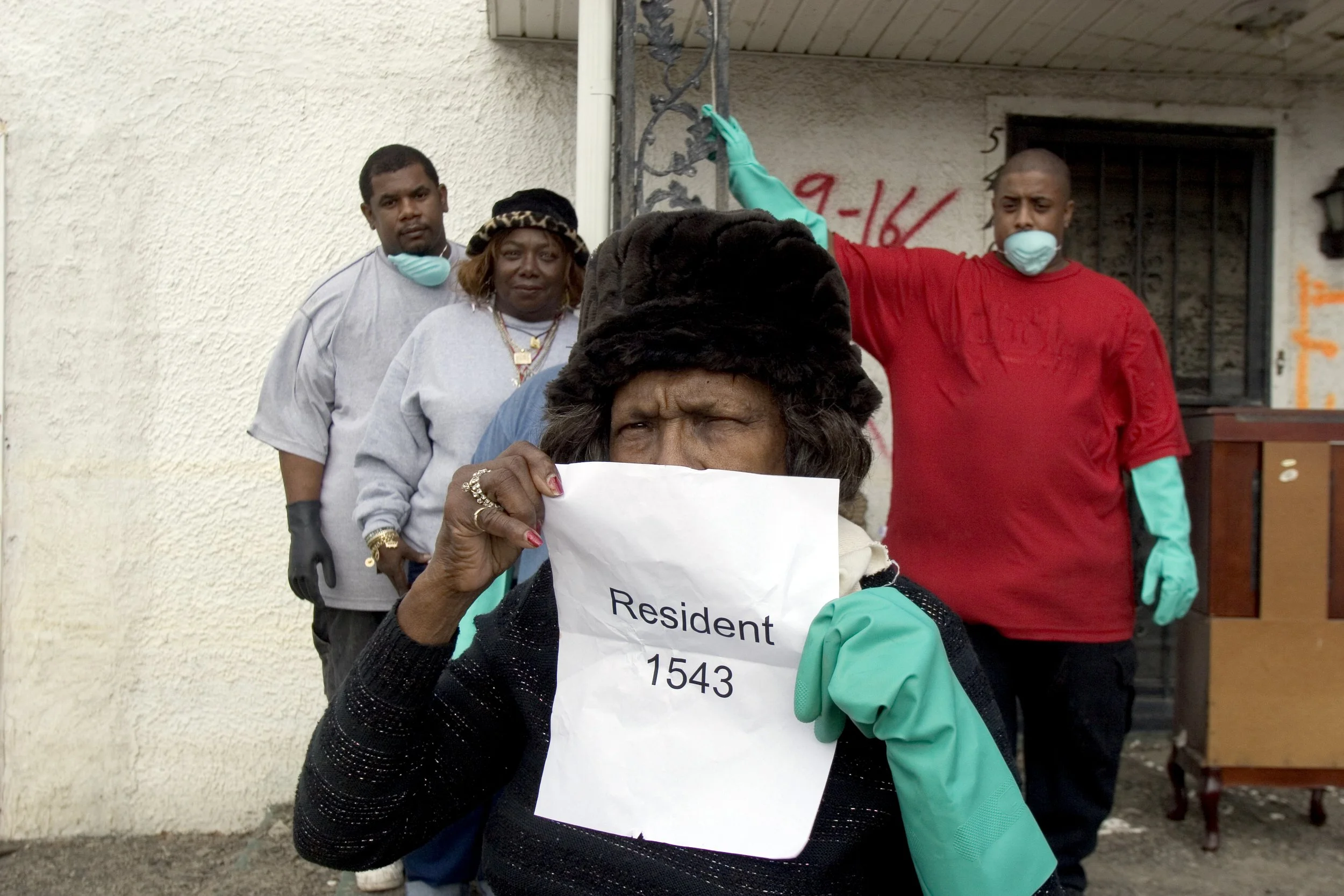 Residents of the lower ninth ward in New Orleans, Louisiana pose in front of their flooded home. “Resident 1543” is the number assigned to them by the National Guard patrolling the neighborhood.