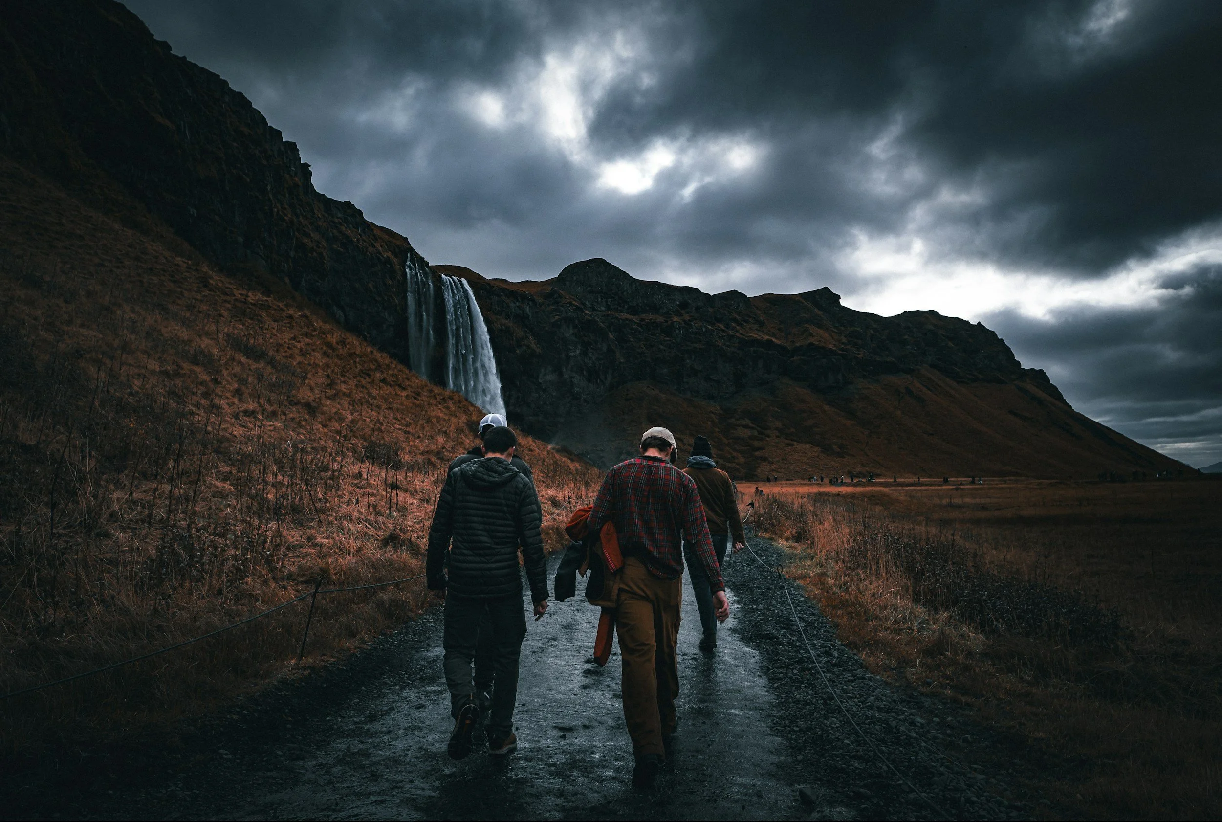 men hiking toward waterfall