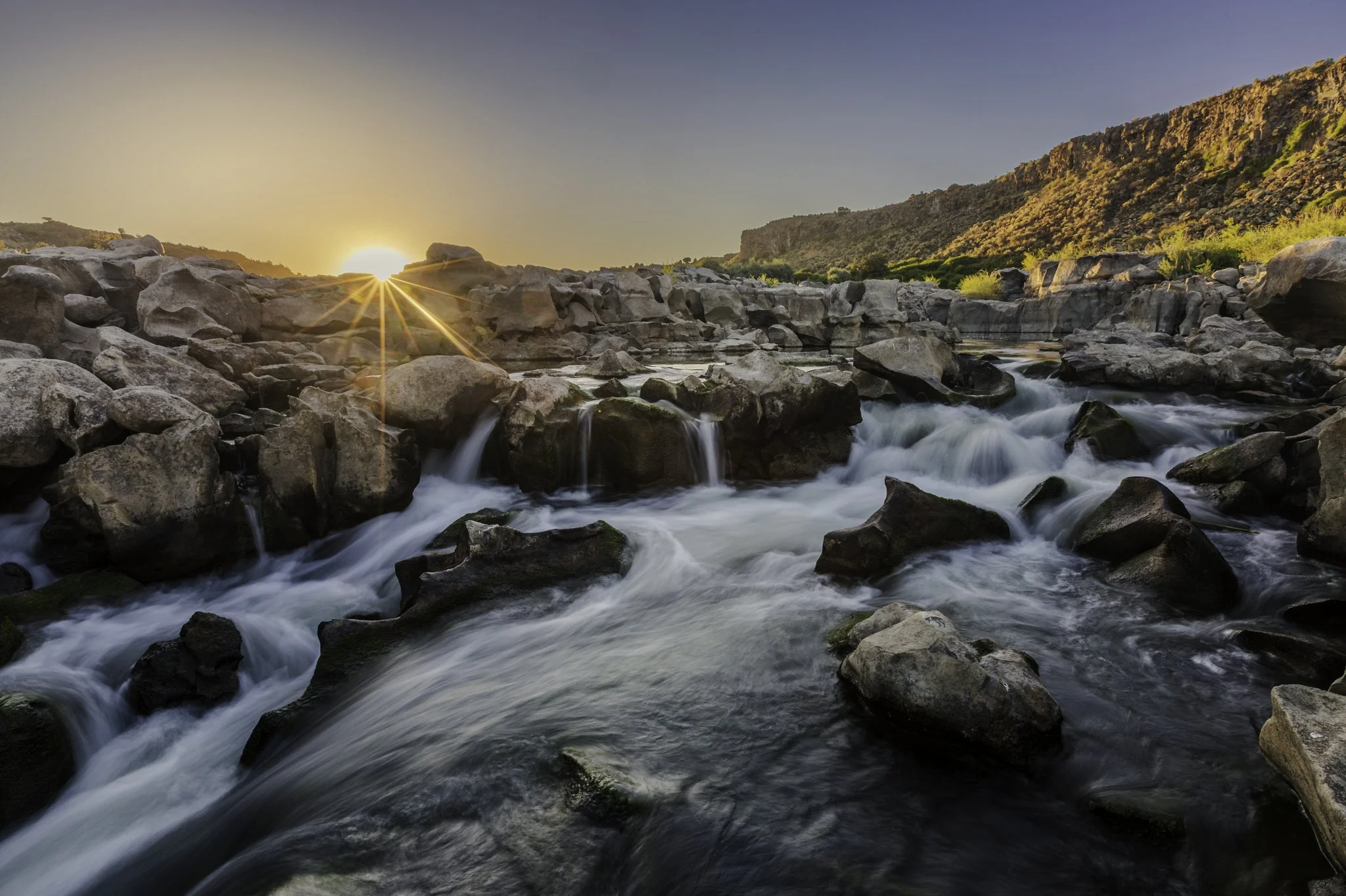 The Sun peers over basalt rock formations shaped by the flowing waters of the Snake at Cauldron Linn
