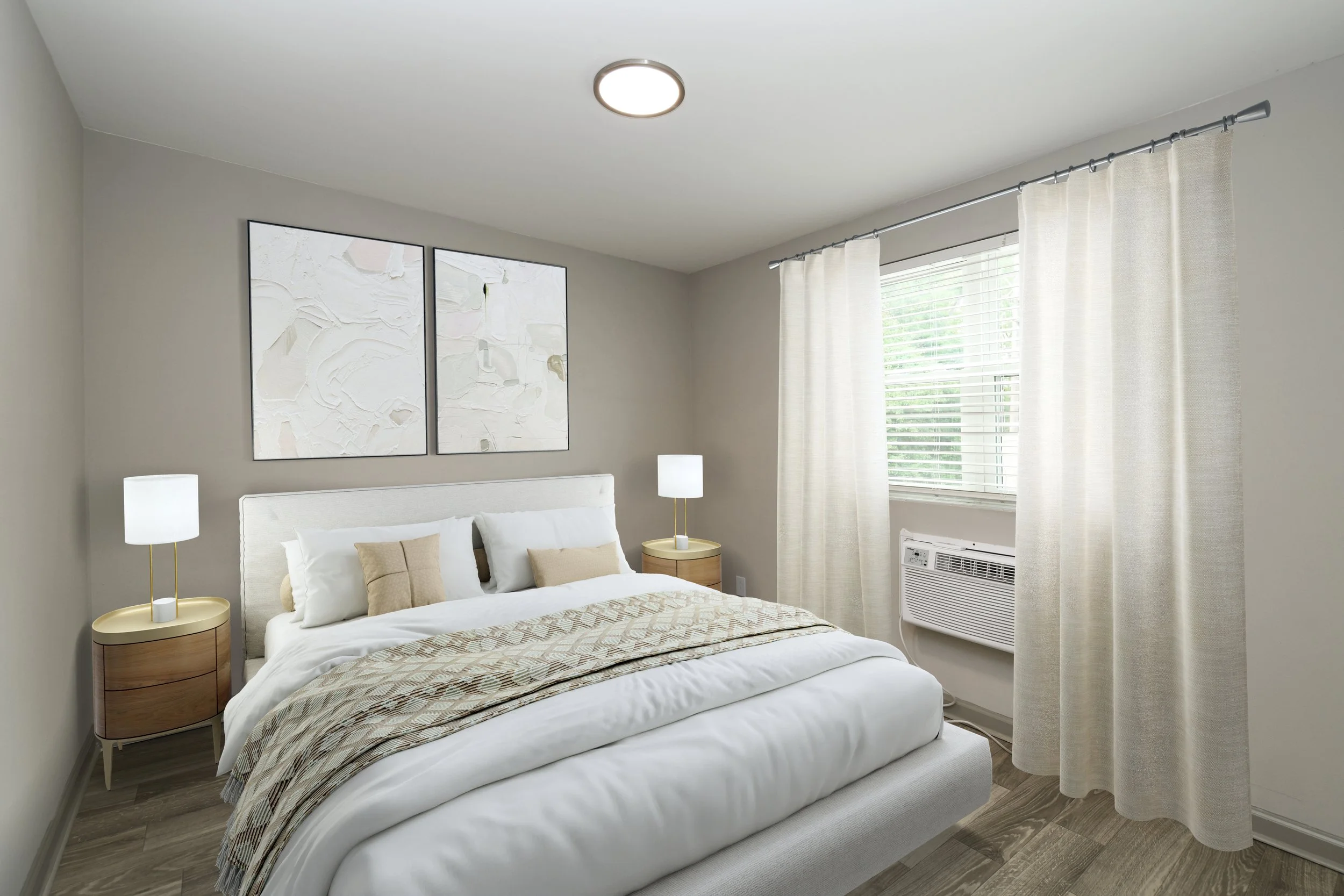Neatly made bedroom with white bedding, beige pillows, and abstract wall art. Two matching nightstands with lamps, window with white curtains, and a window air conditioner.