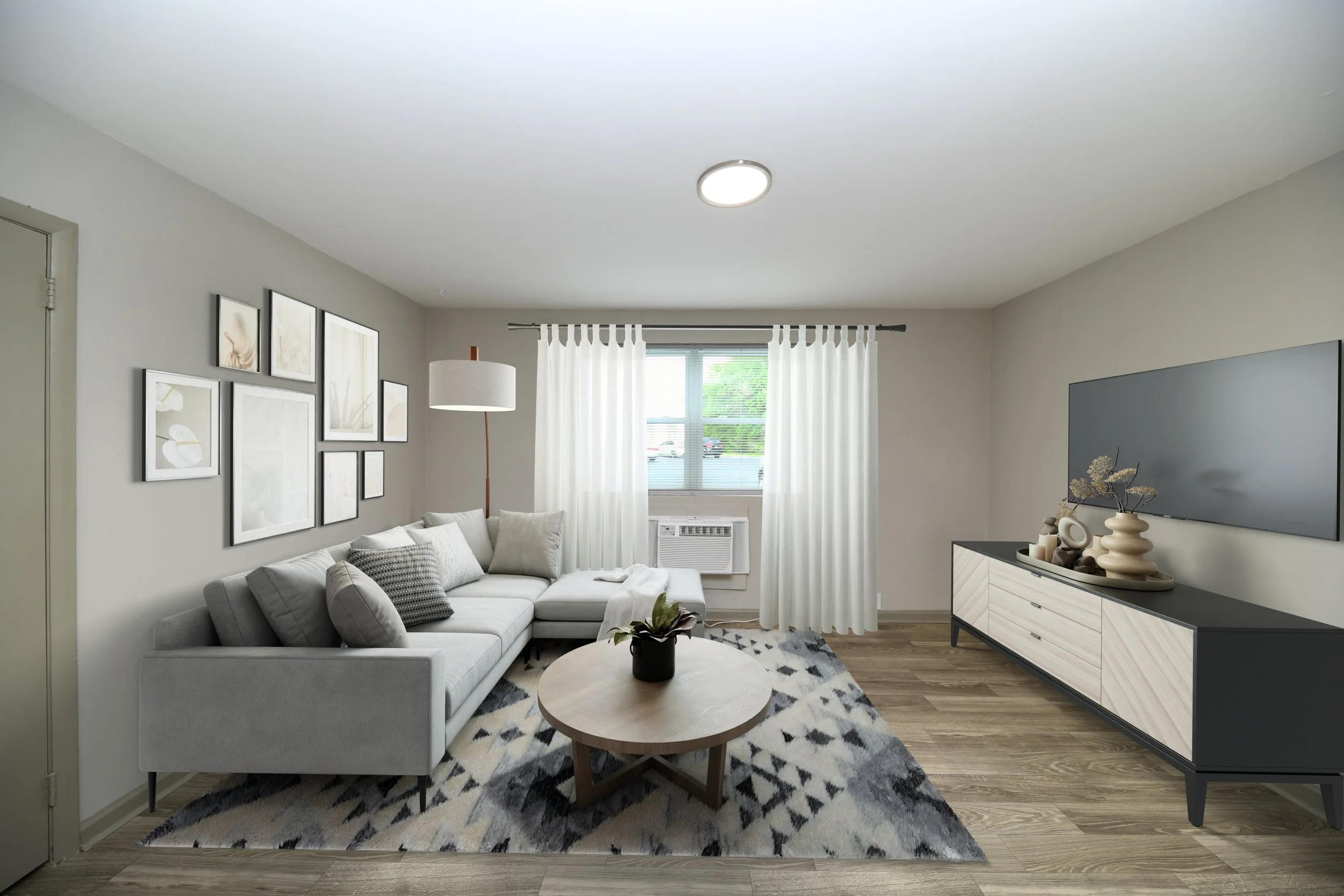 Modern living room with light gray sofa, abstract art on the wall, white curtains, wood floor, and a black and beige console holding decorative objects