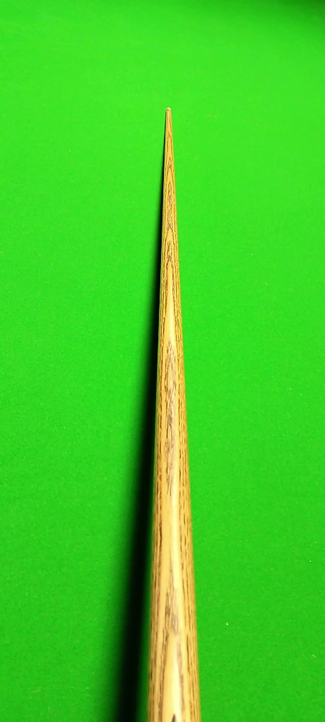 A close-up image of a wooden golf tee on a bright green surface.