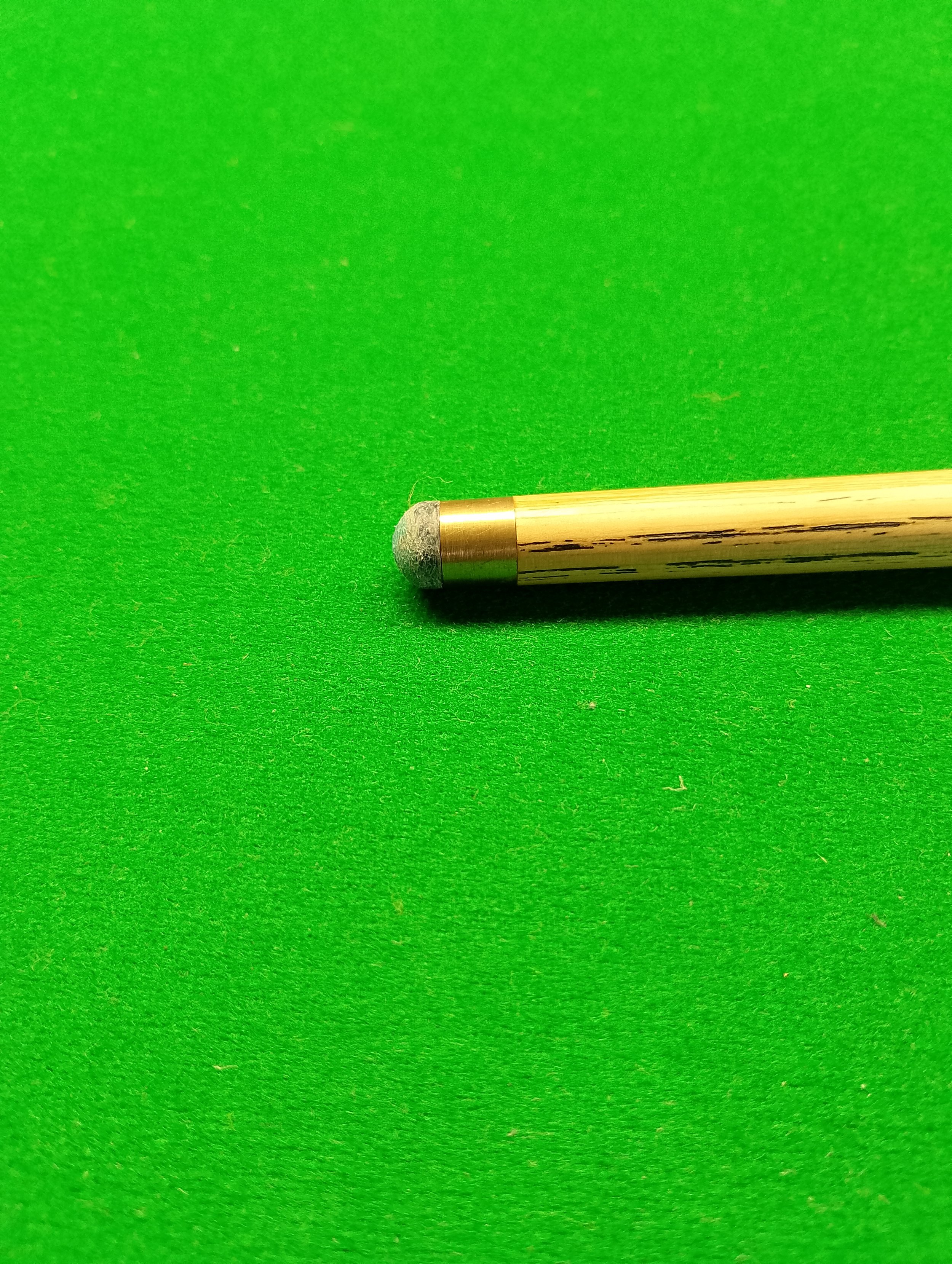 A cue stick lying on a green pool table felt surface.