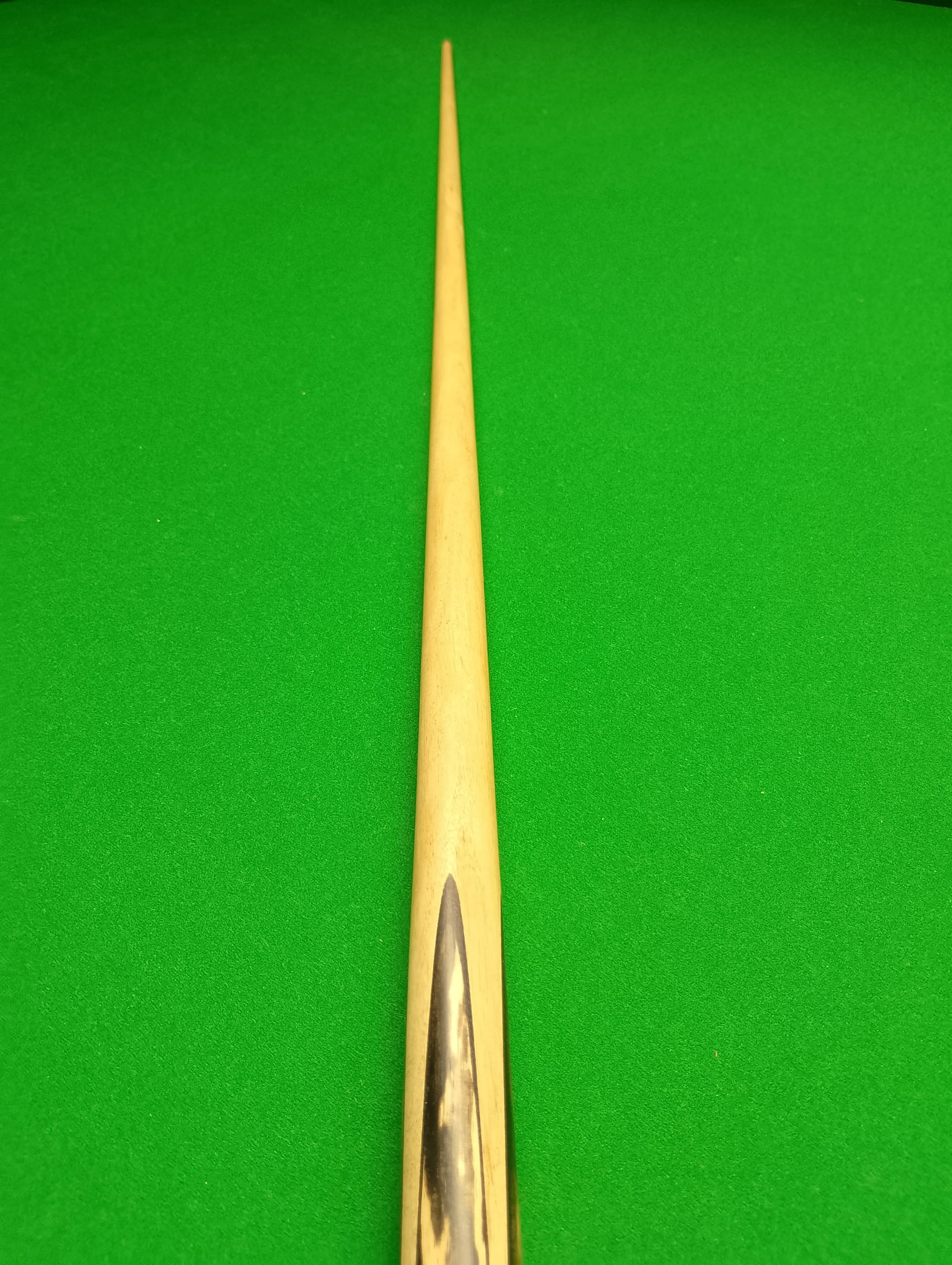Close-up of a cue stick on green pool table felt.