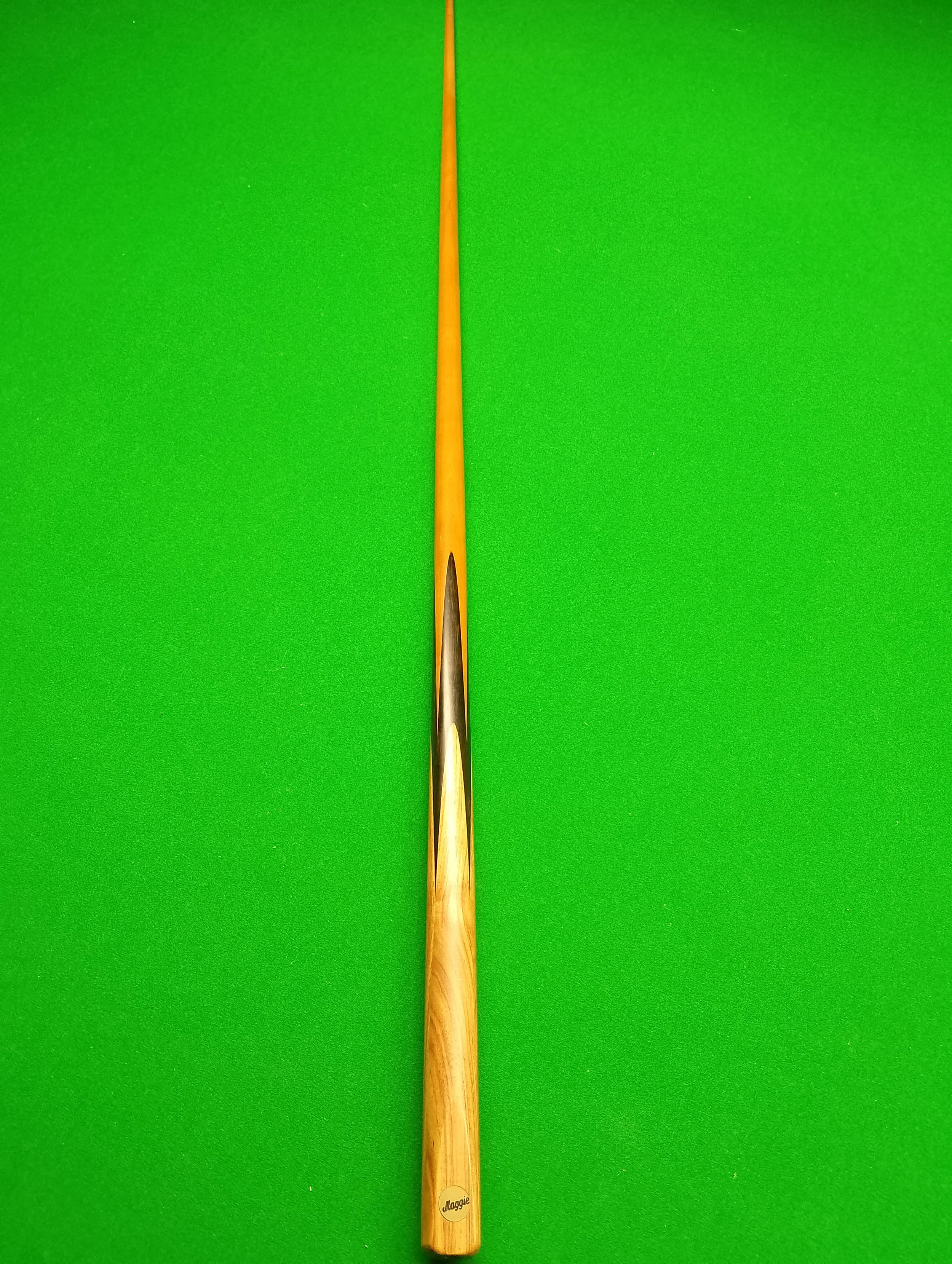 A pool cue lying on a green pool table.