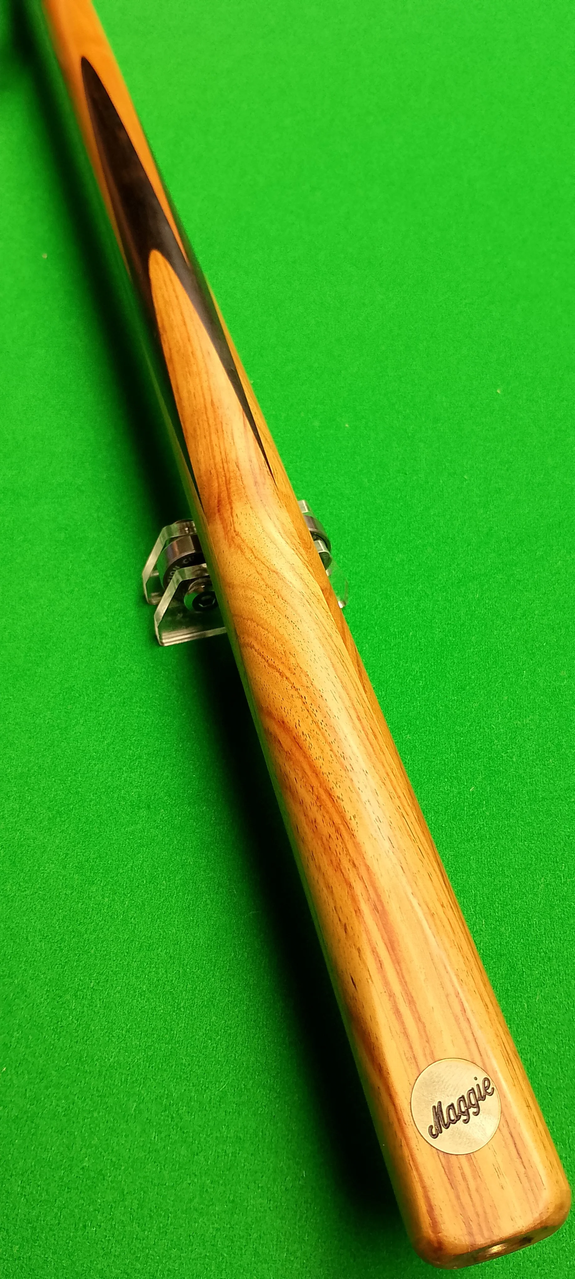A wooden cue stick resting on a cue stand on a green pool table.