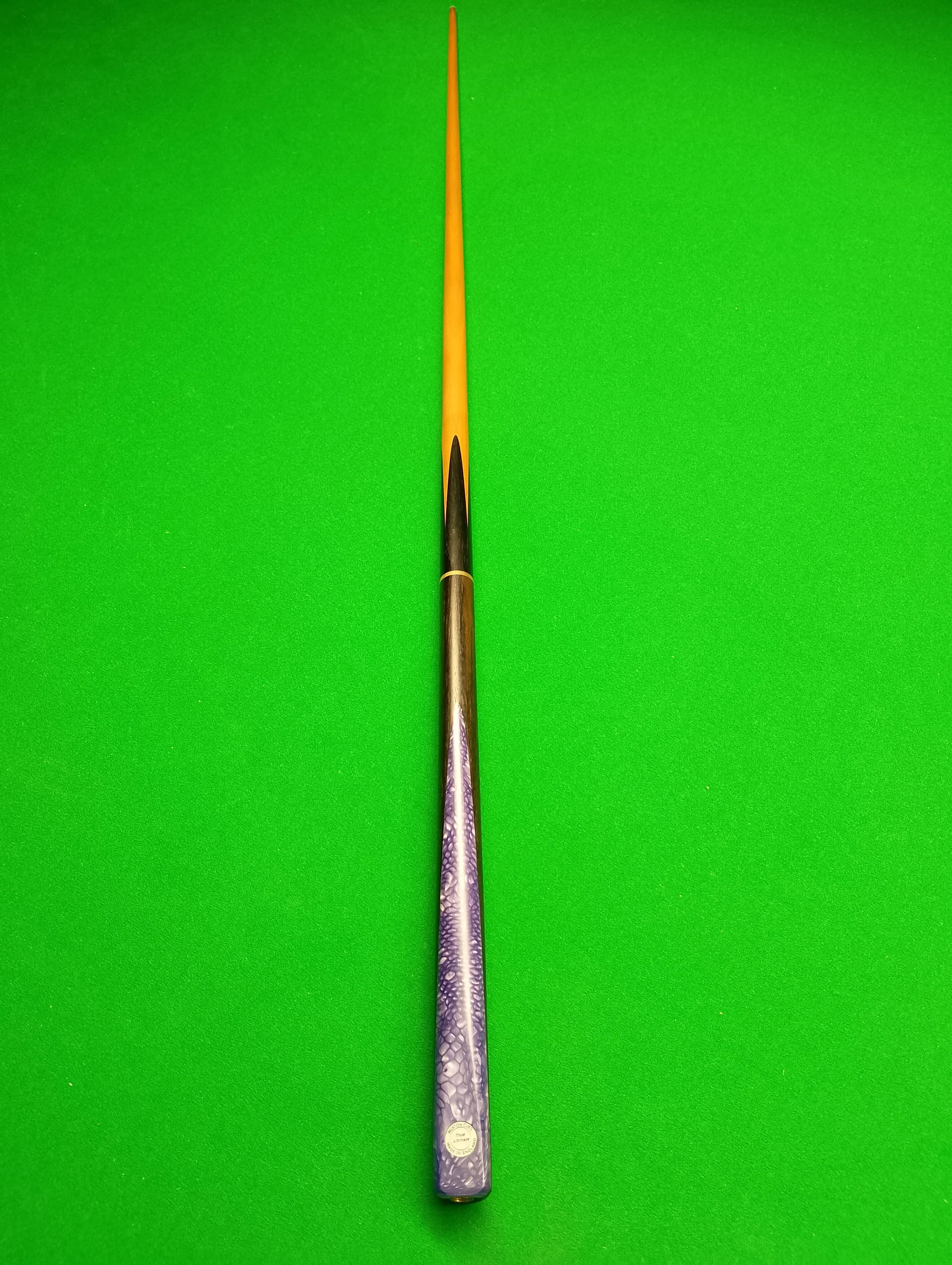 A billiard cue stick lying on a green pool table.