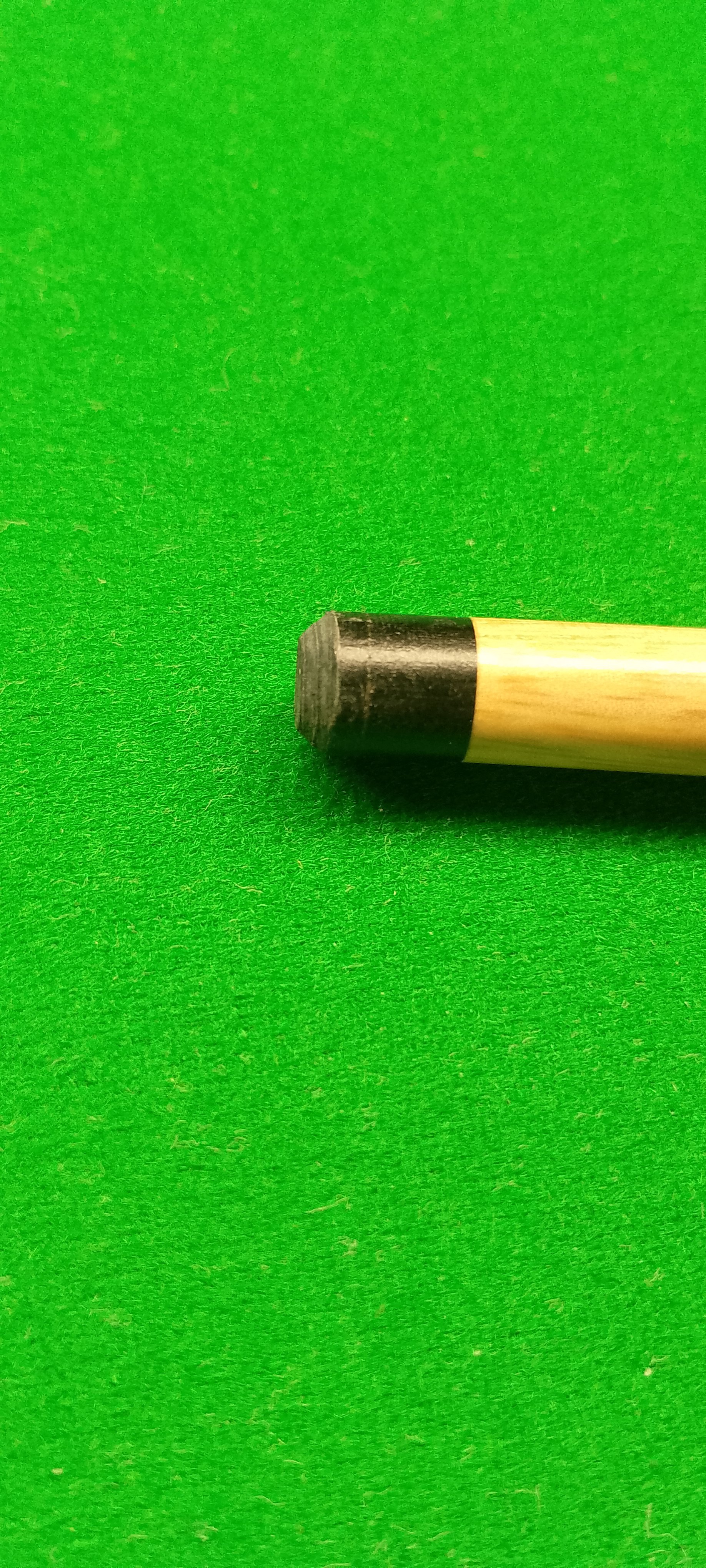Close-up of a cue stick tip on a green pool table surface.