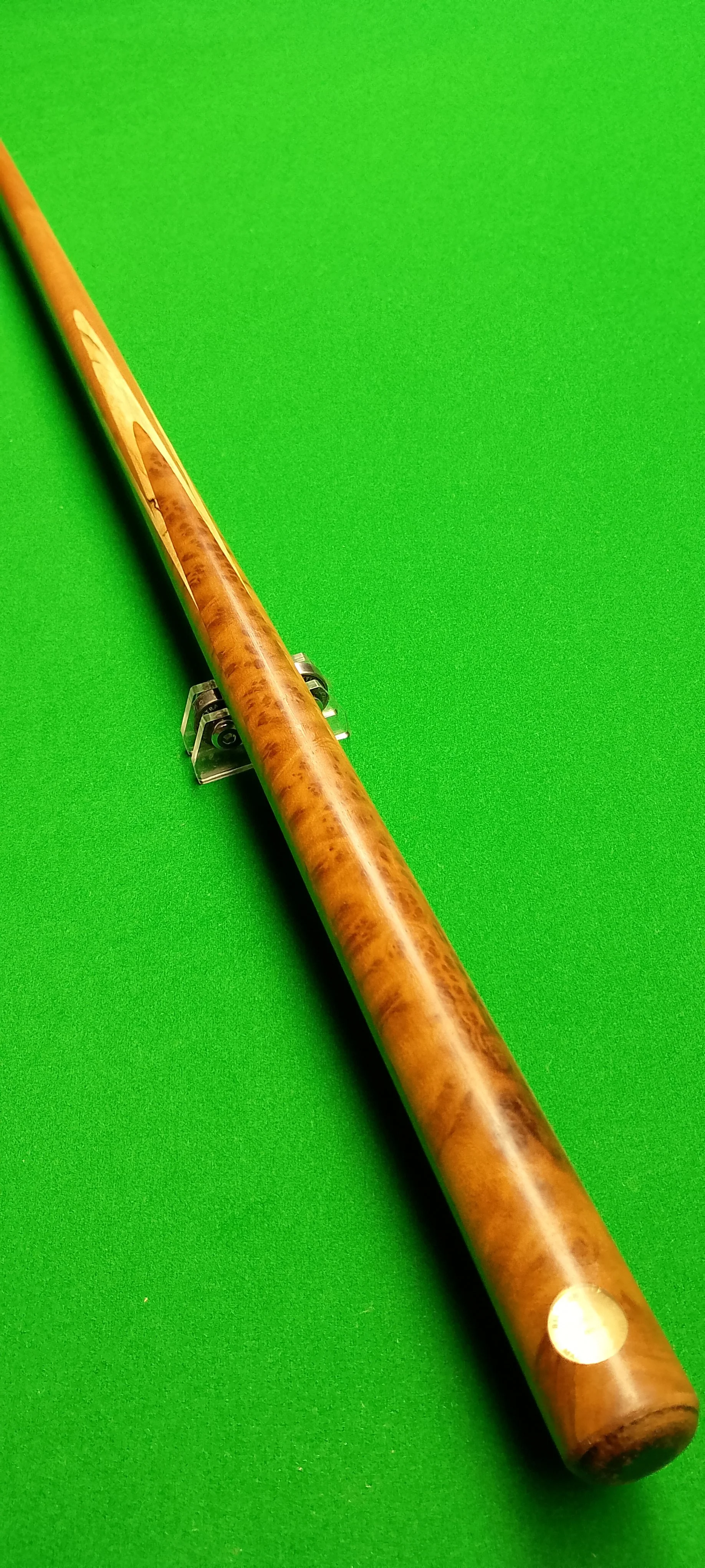 Billiard cue stick lying on a green pool or billiard table.