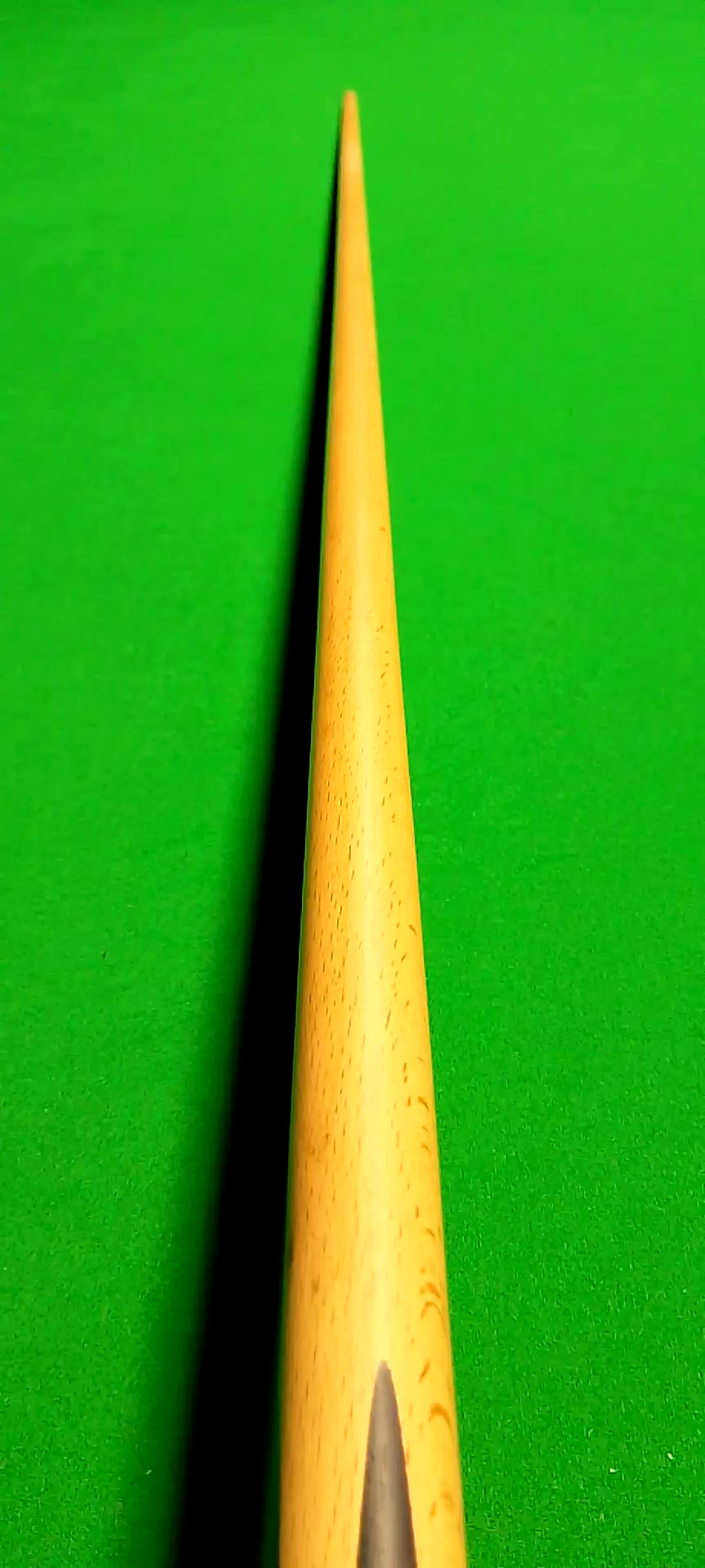 Close-up of a yellow pool cue stick on a green pool table.