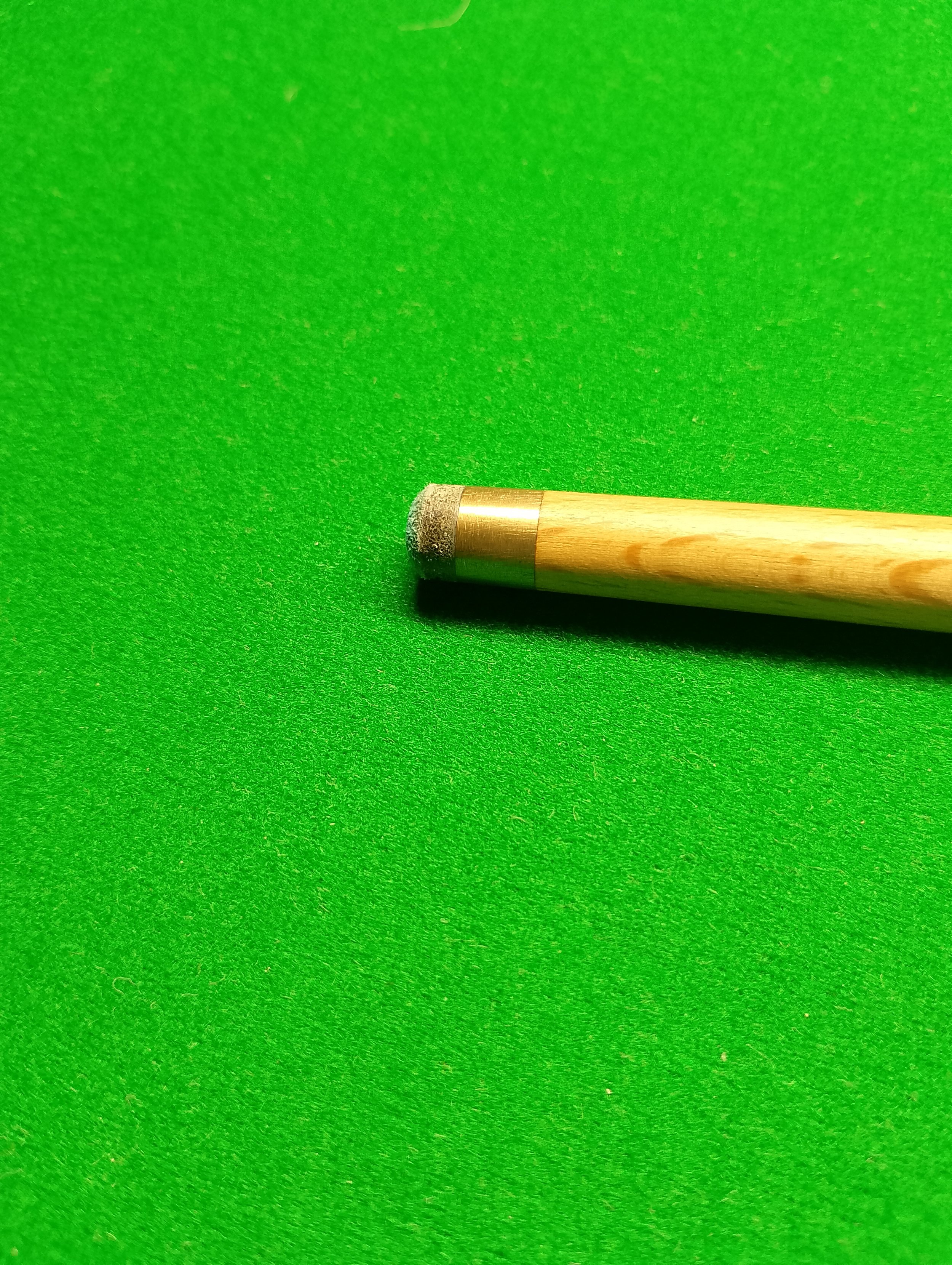 A pool cue resting on a green billiards or snooker table surface.