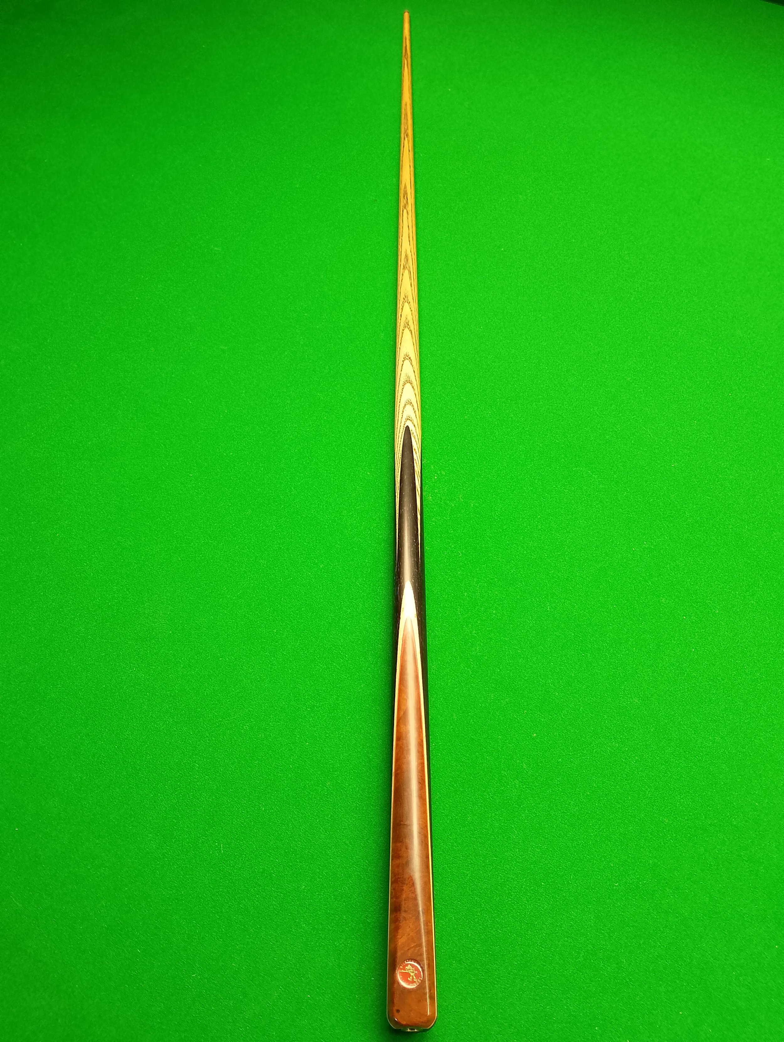 Pool cue stick on a bright green pool table surface, centered vertically in the image.