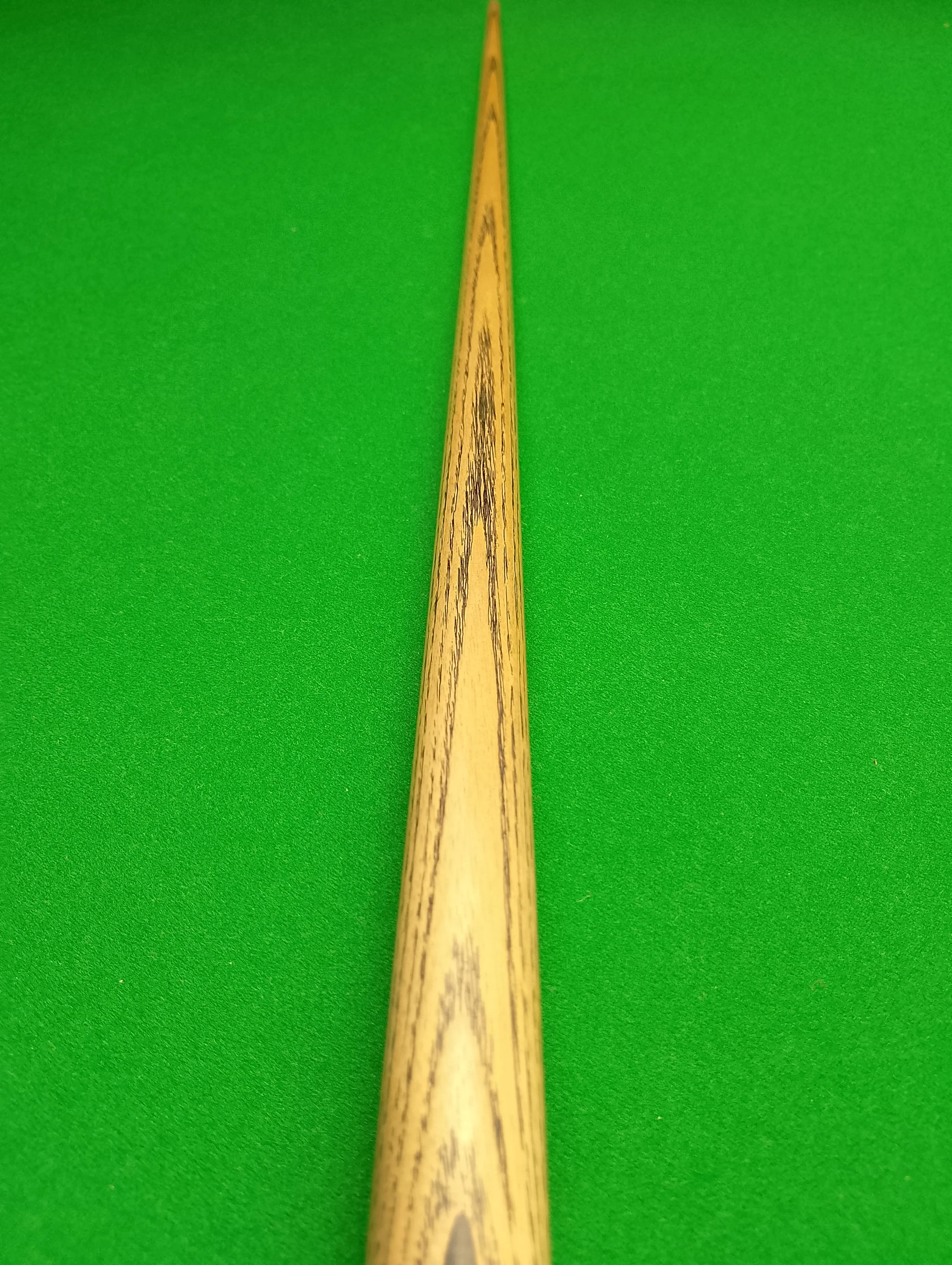 Close-up of a billiard cue on a green billiards table.