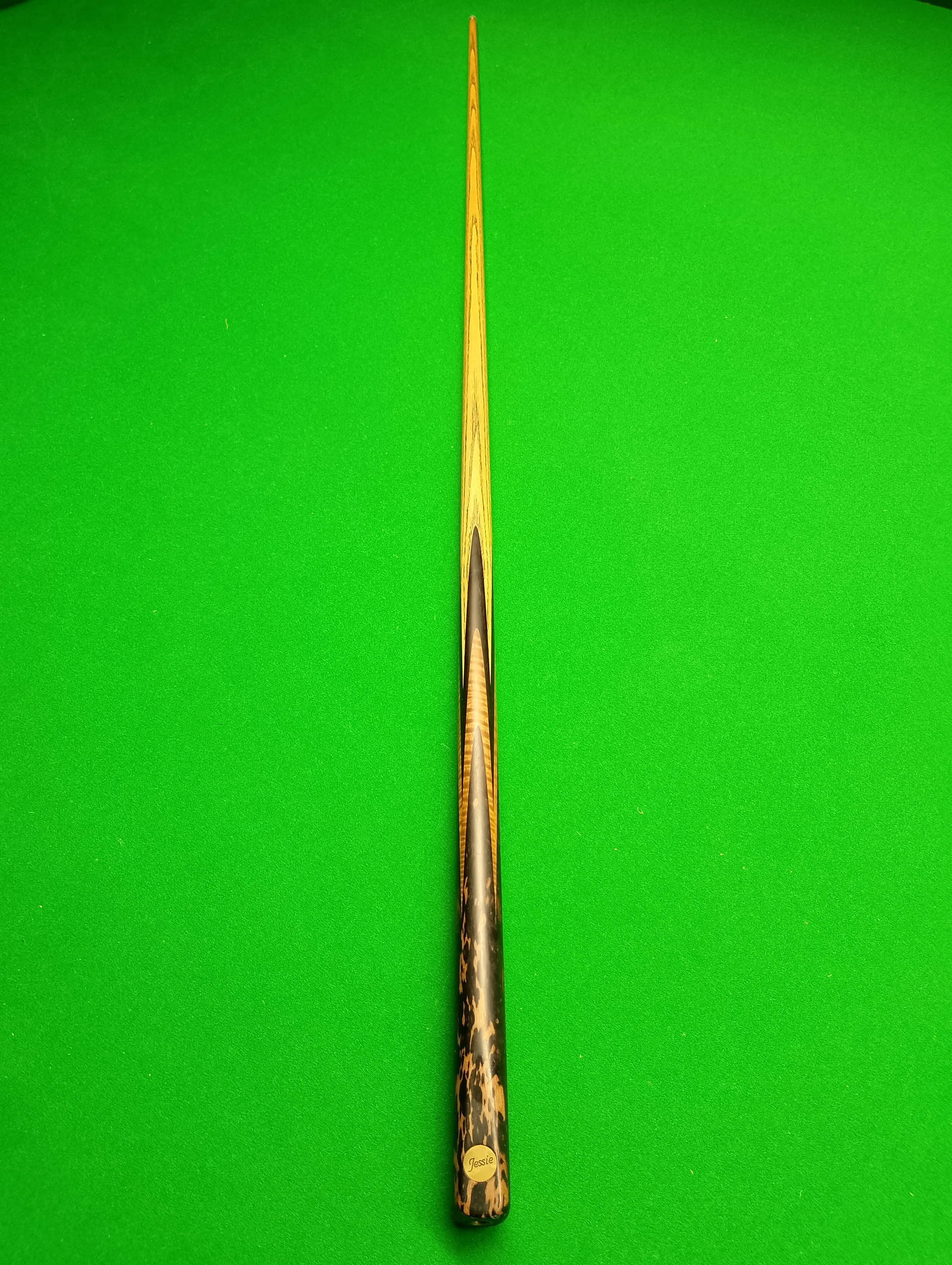 Pool cue stick with a wooden grip resting on a green pool table.