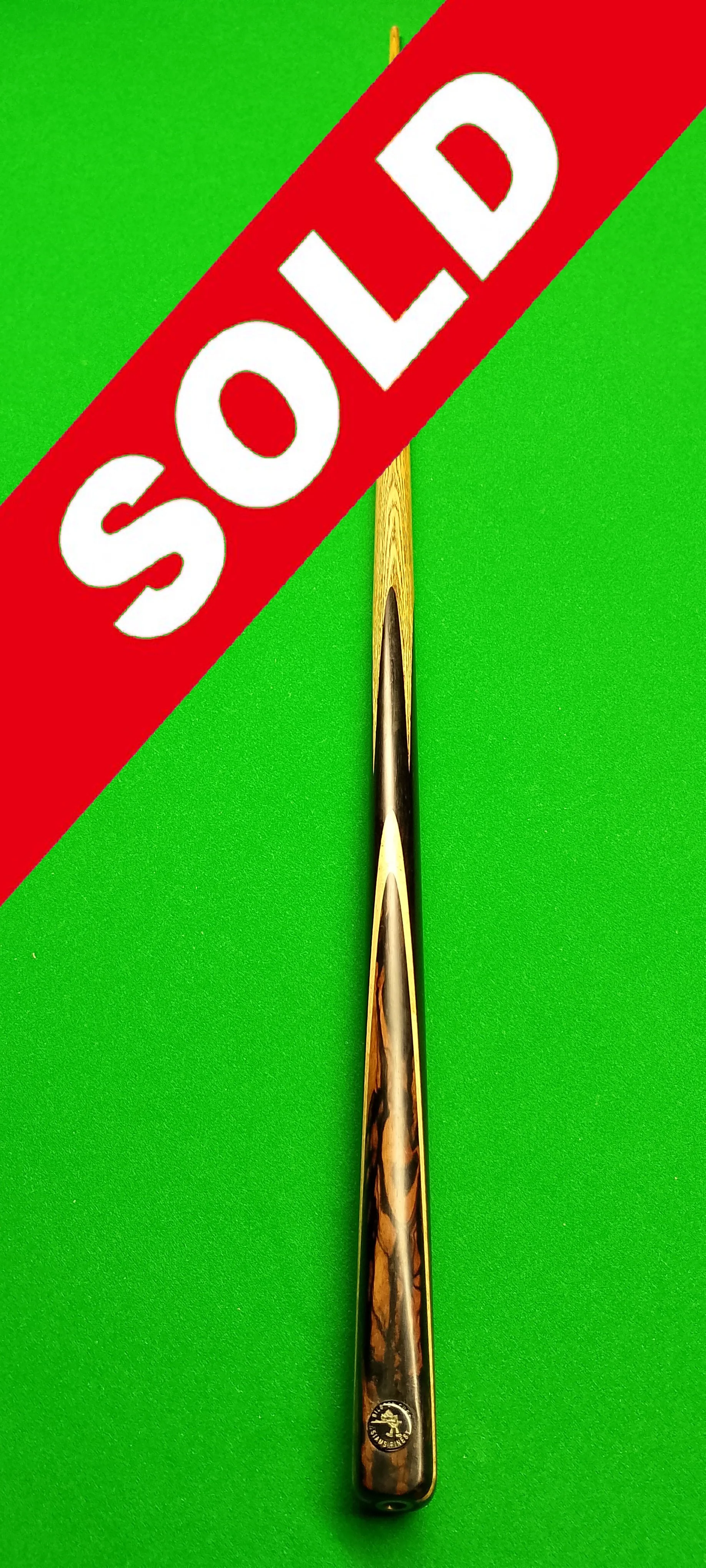 A pool cue stick with a tortoiseshell pattern on the handle, placed upright on a green pool table, with a red "SOLD" banner across the top left corner of the image.