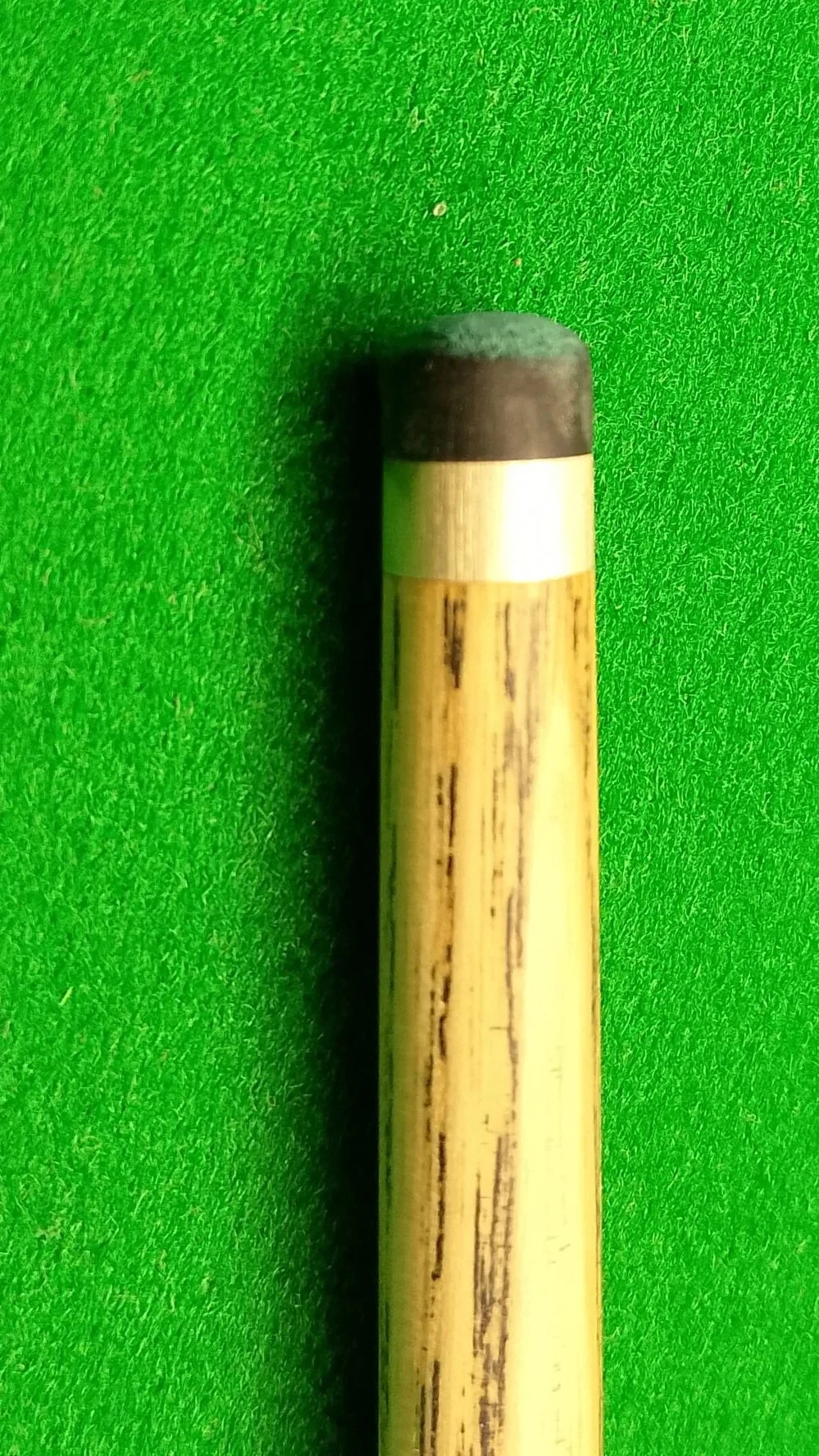 A close-up photo of a billiard cue stick on a green textured background.