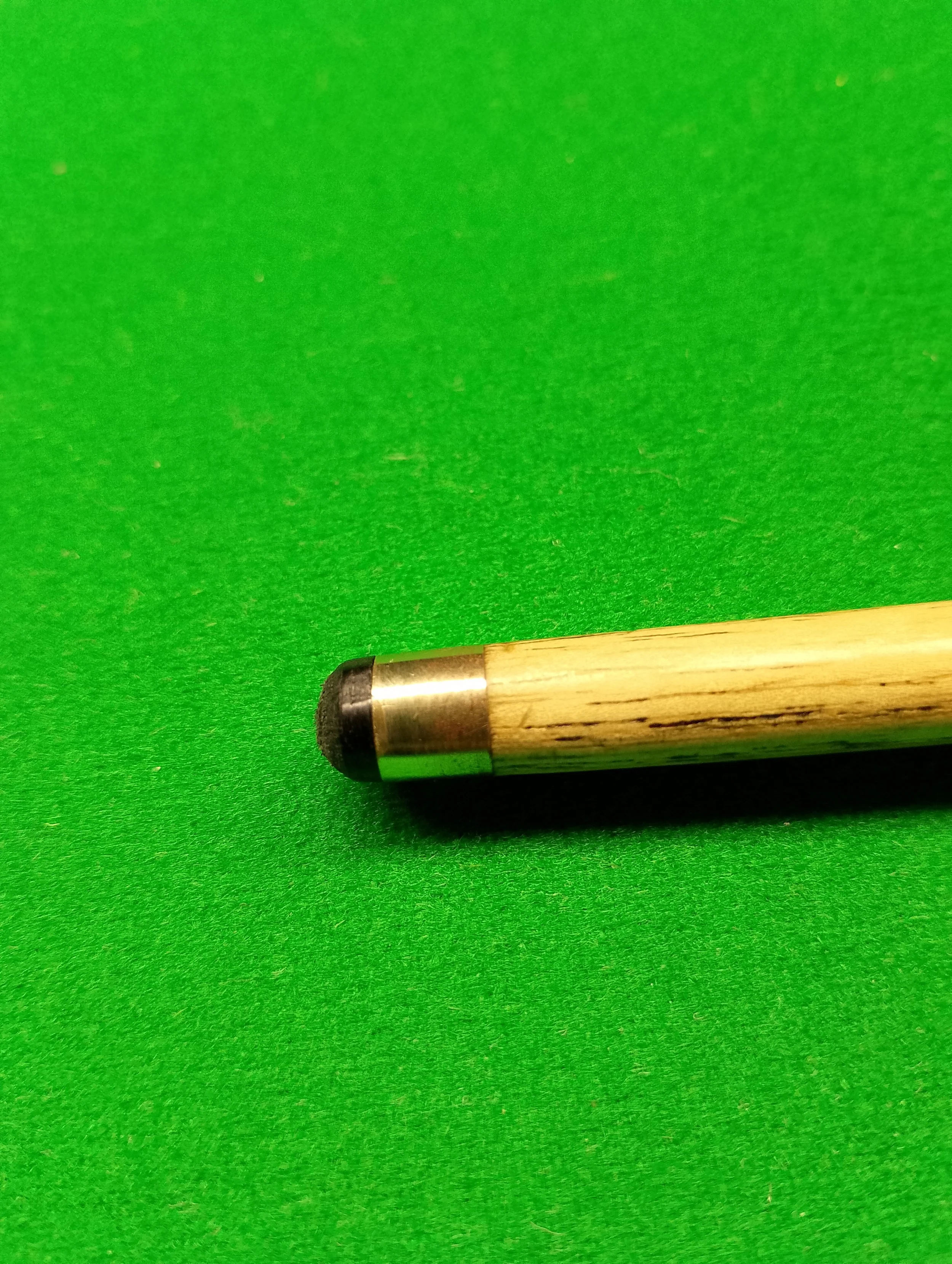 Close-up of a cue stick tip on a green billiard or pool table surface.