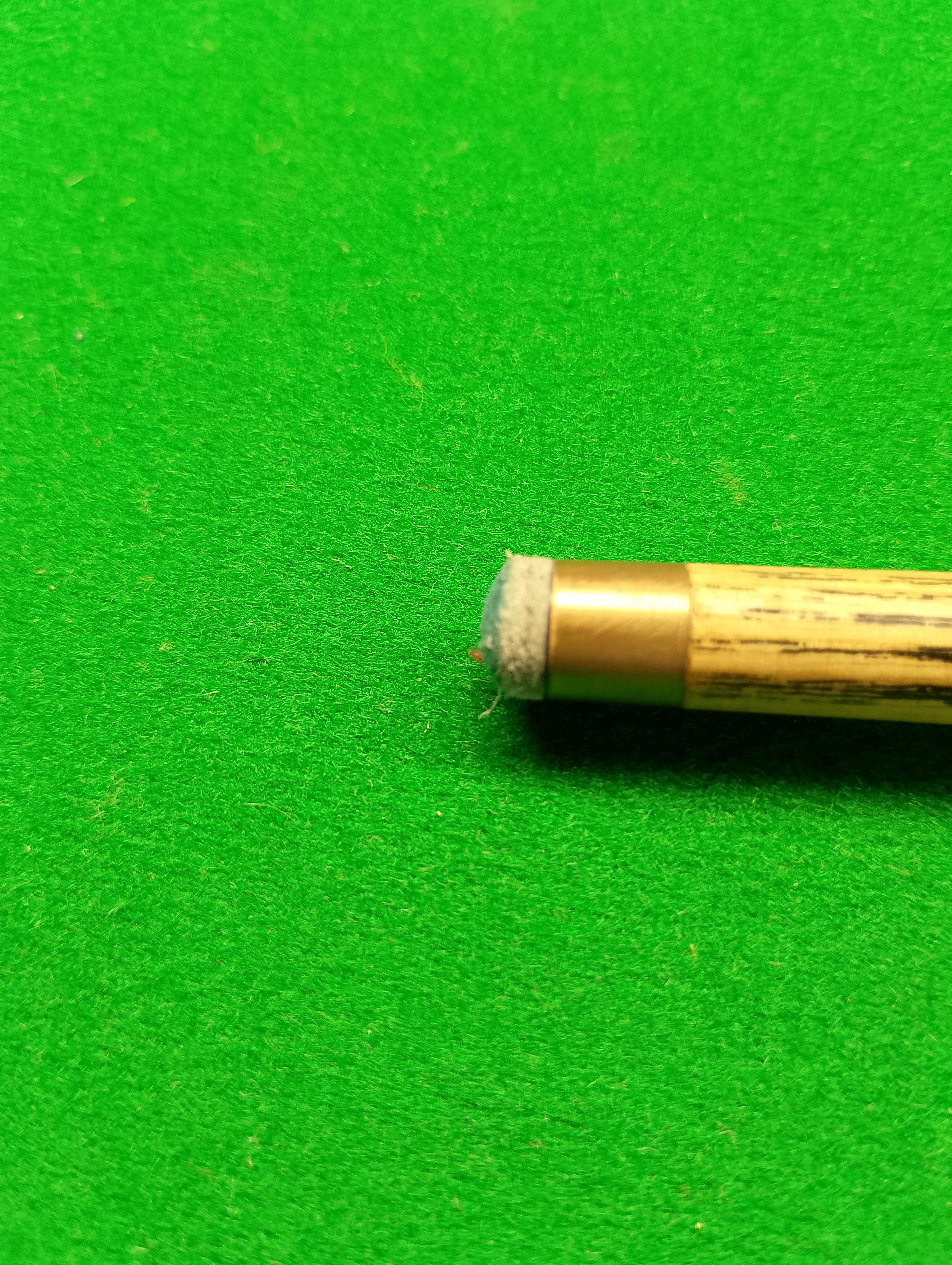 Billiard cue tip on a green felt pool table.