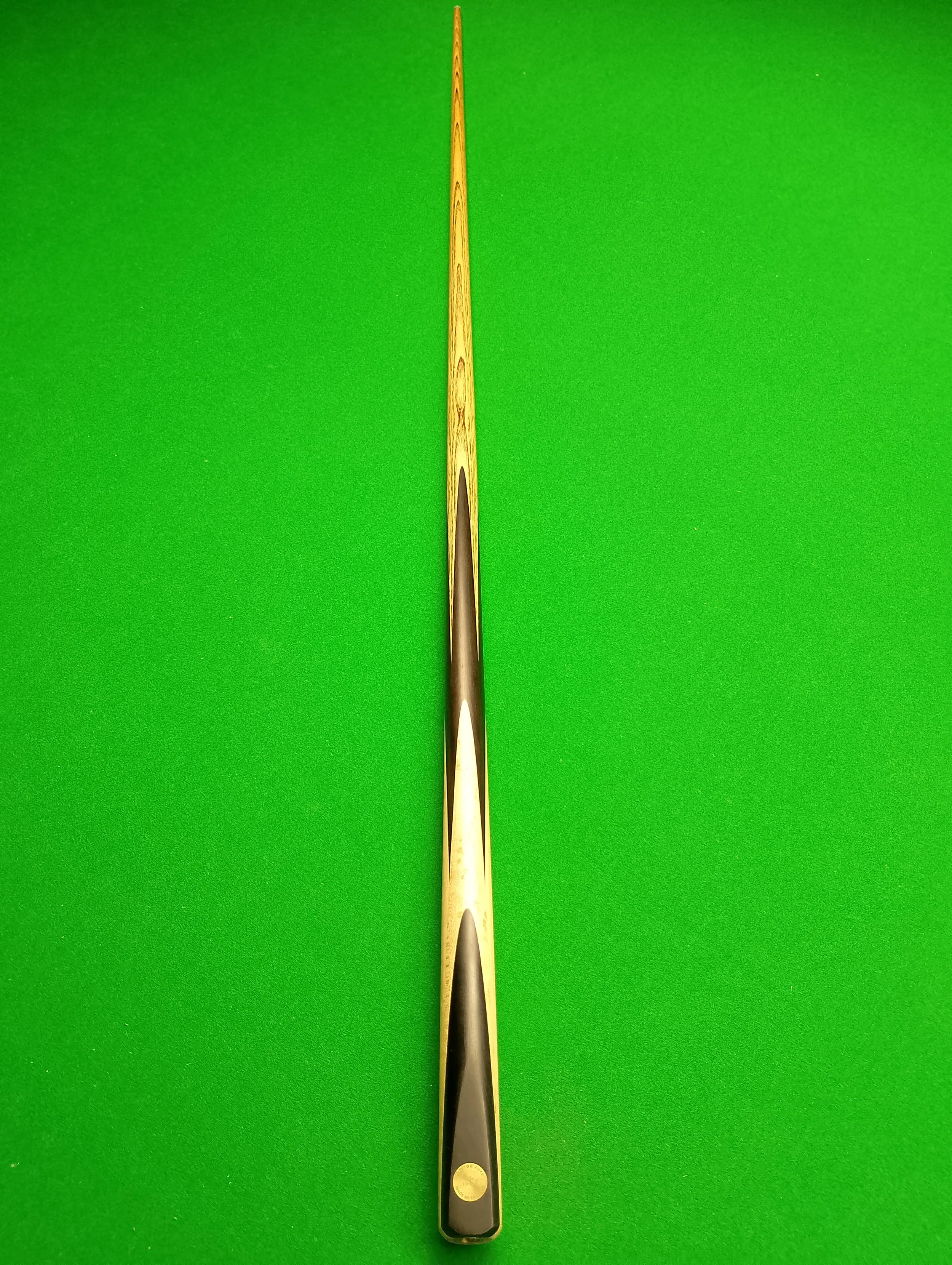 A pool cue stick laid flat on a green pool table.