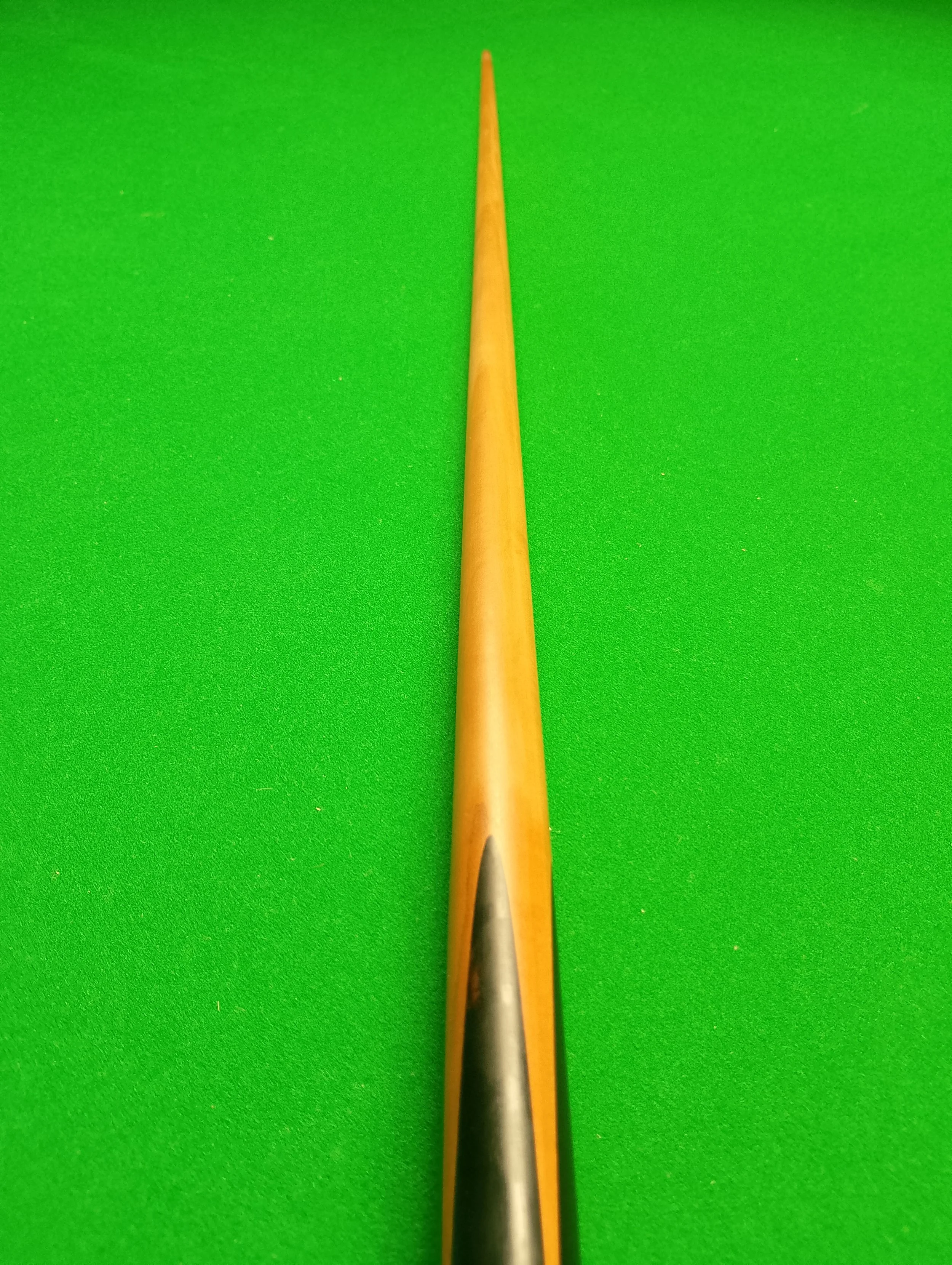 Close-up of a snooker cue on a green snooker cloth.