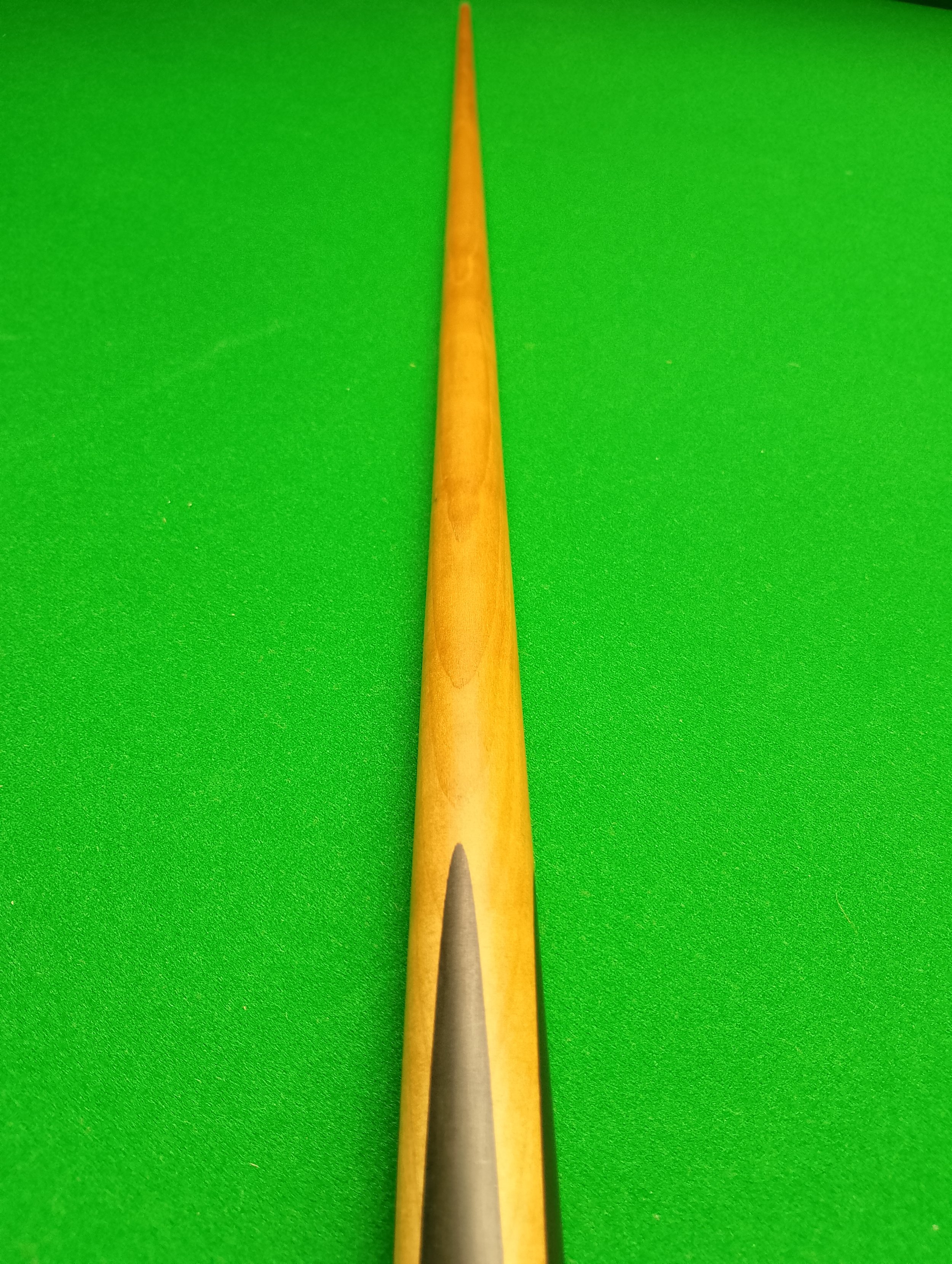 Close-up of a snooker cue on a green pool table.