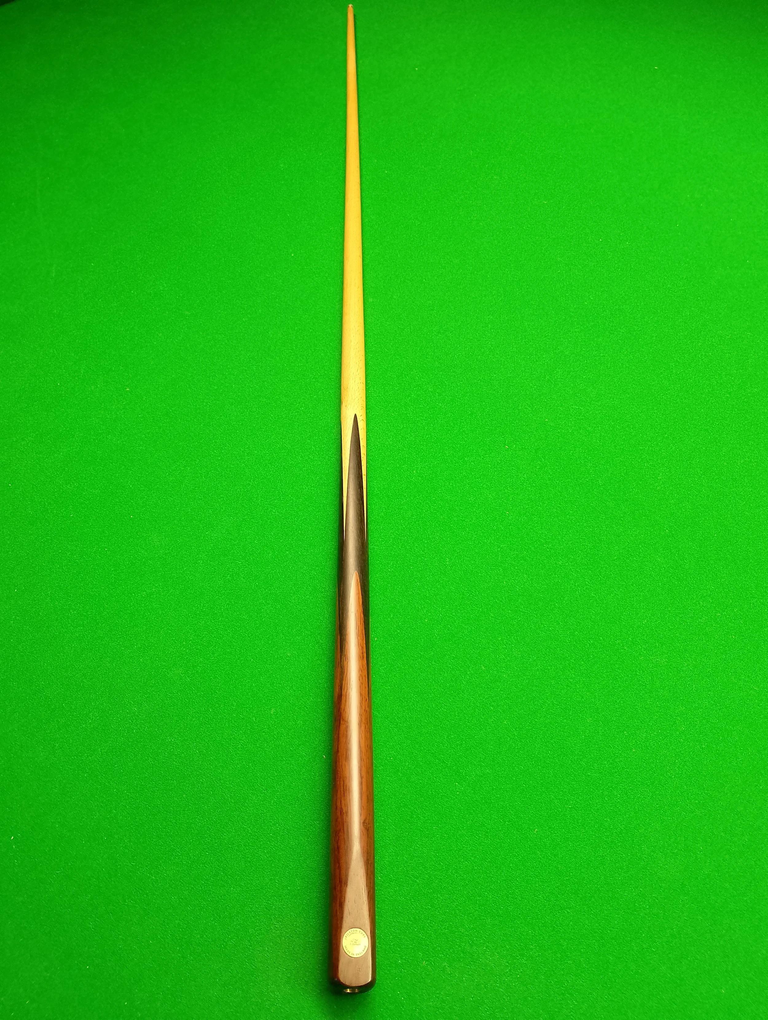 A cue stick for billiards or pool on a green felt table.