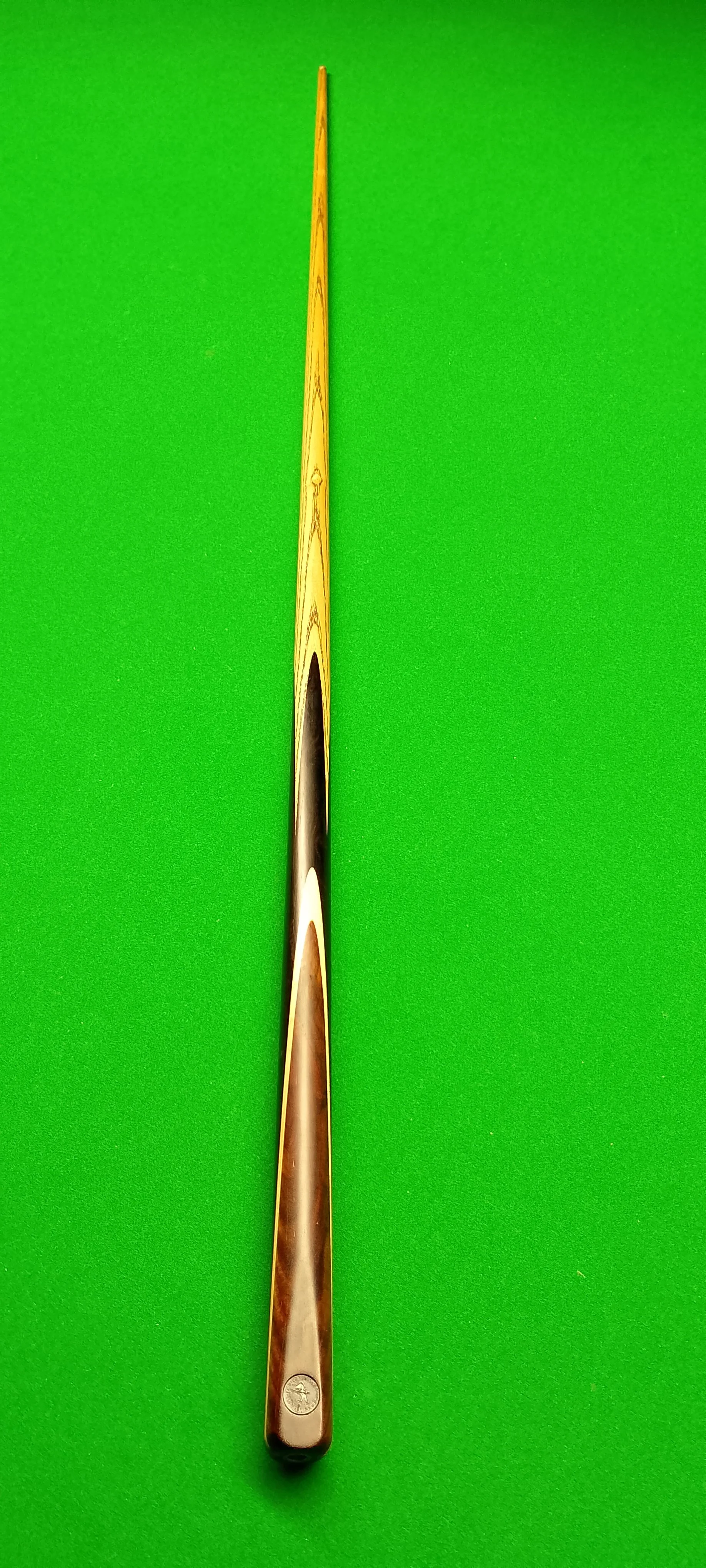 A cue stick for billiards or pool on a green felt table.