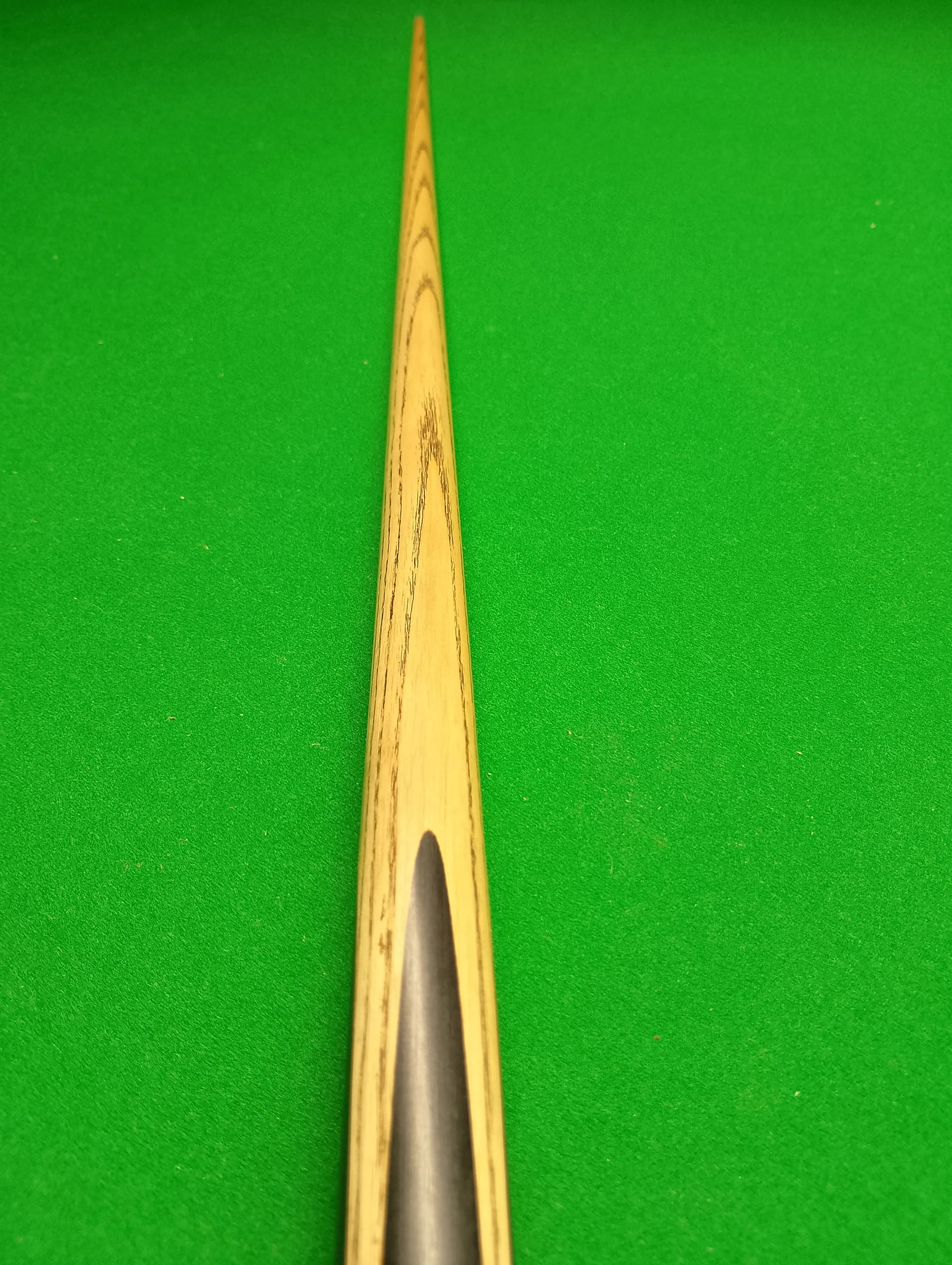 Close-up of a billiard cue stick on a green pool table.