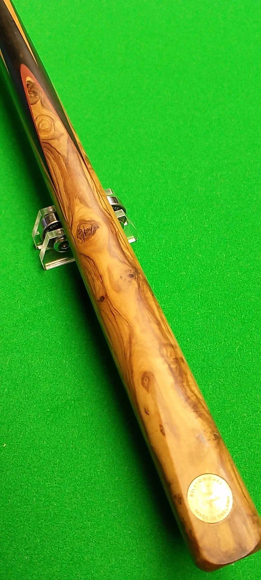 A knife with a handle made of polished wood with natural grain patterns, set against a bright green background.