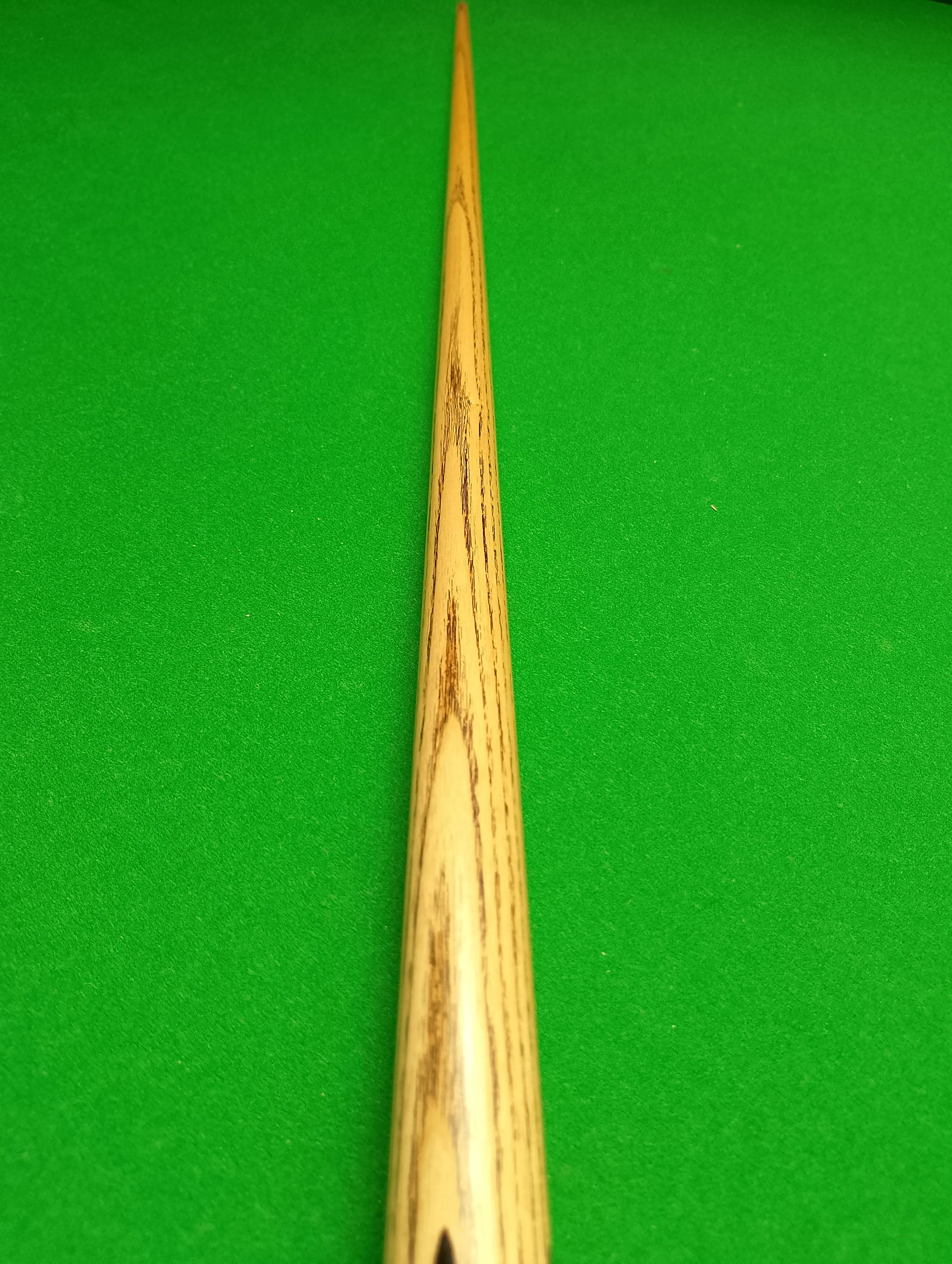 A wooden cue stick on a green felt pool table.