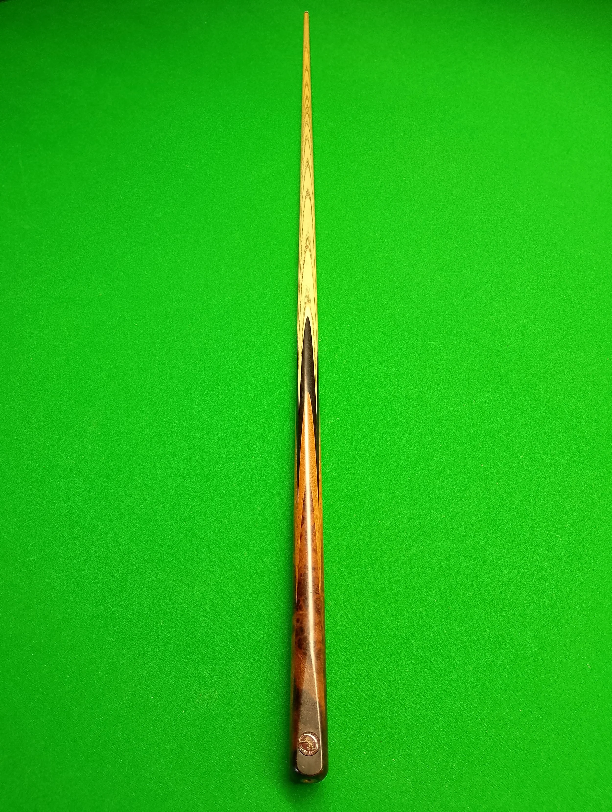A pool cue stick lying flat on a bright green surface