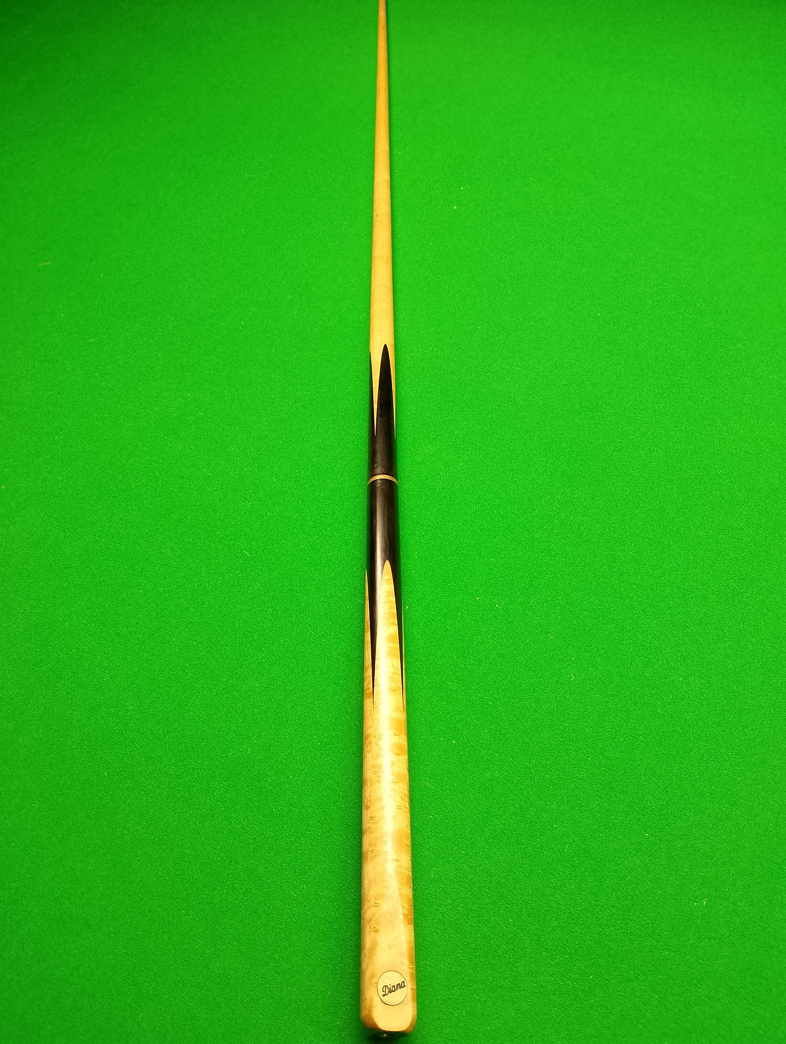 A snooker cue stick lying on a green snooker table.